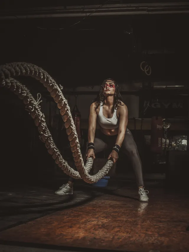 Athlete driving battle ropes under a single overhead light