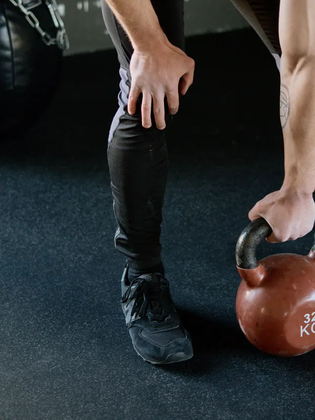 Athlete gripping a 32 kilogram kettlebell on the gym floor