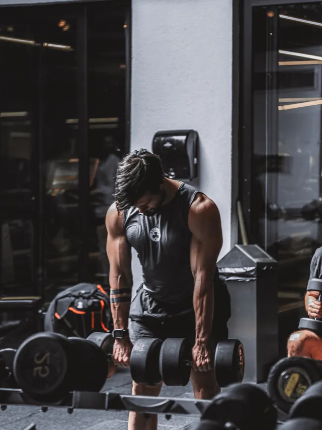 Athlete rowing a heavy dumbbell in a dark training room