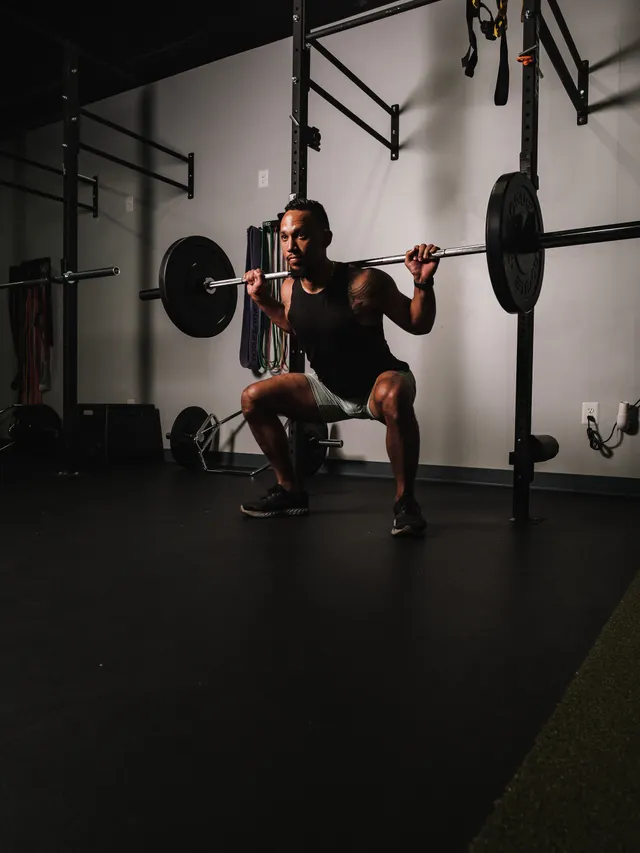 Lifter descending into a back squat in a quiet training hall