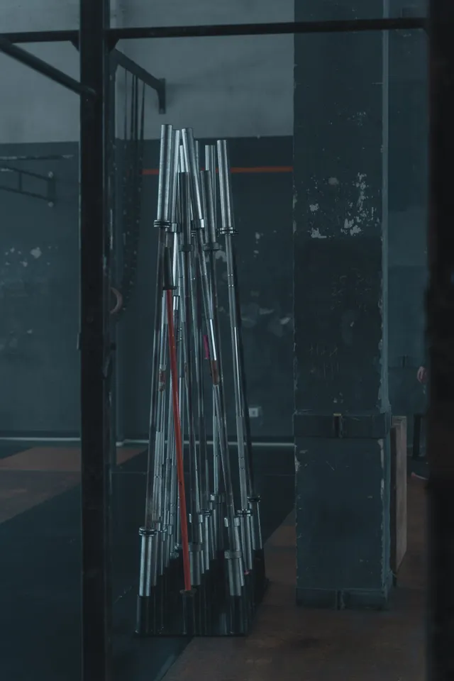 Loaded barbells stored upright in a rack against a dark wall