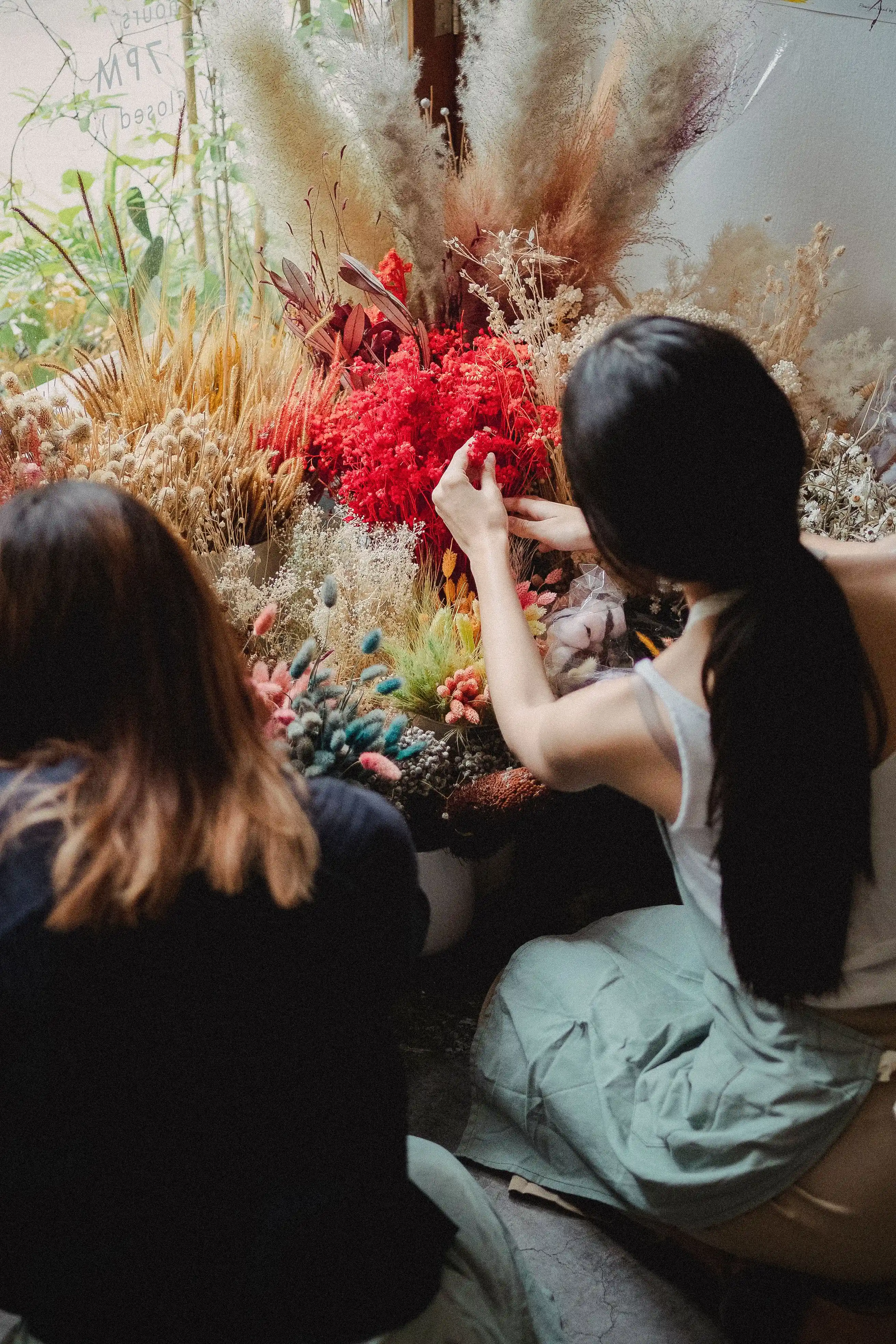 Florists in aprons working at a bench covered in stems