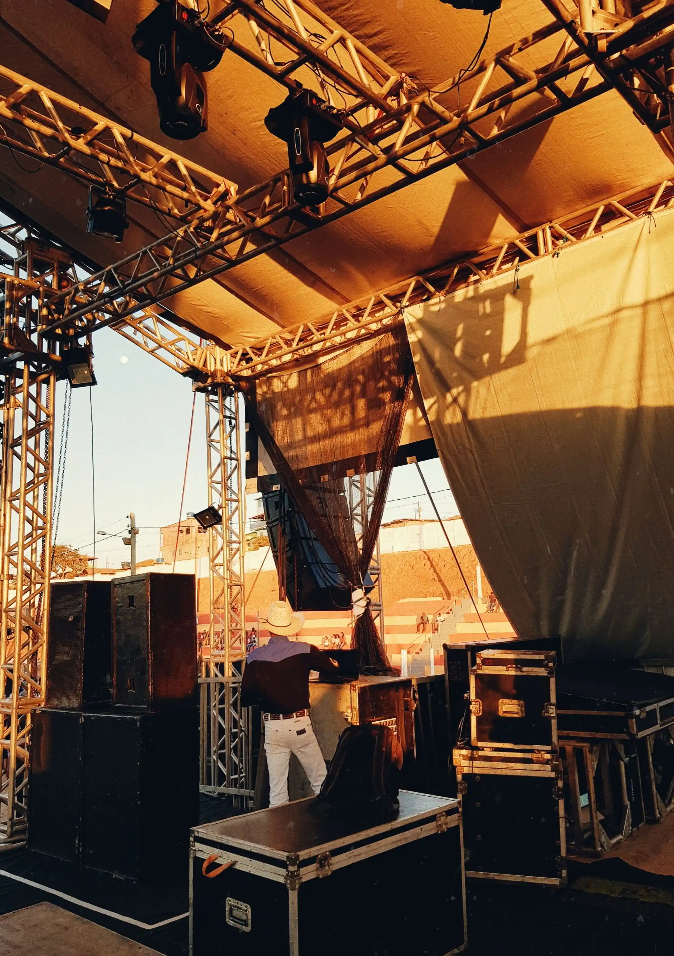 A crew member rigging equipment on stage at sunset