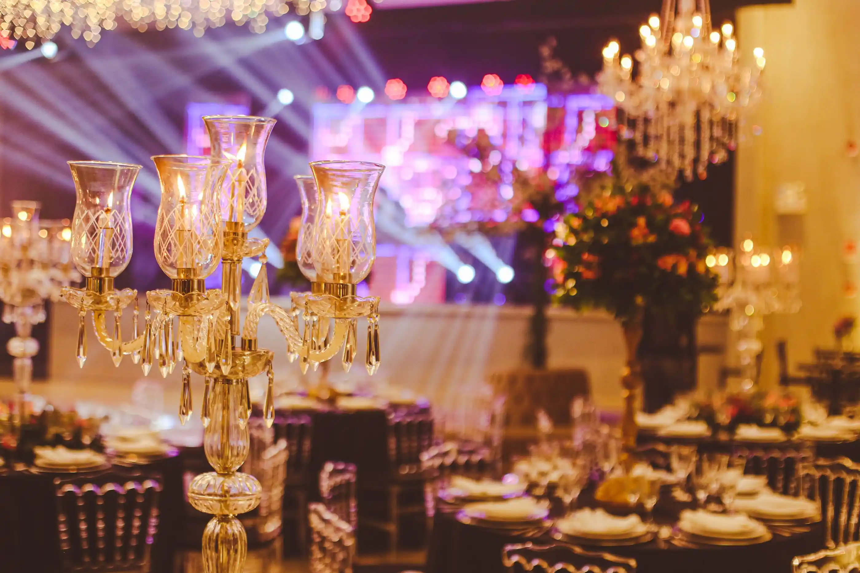 A ballroom laid for dinner with tall crystal candelabra on every table