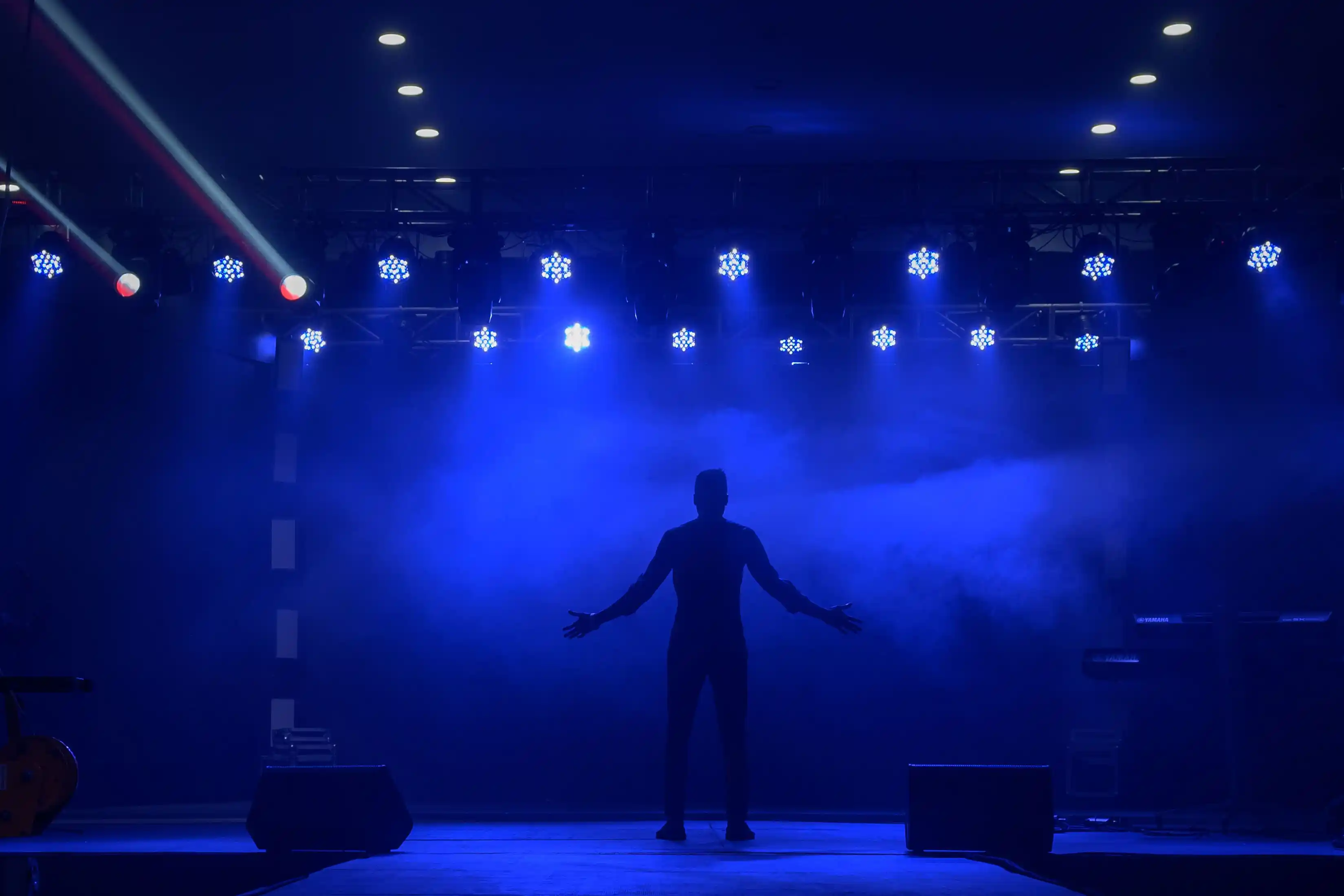 A lone figure silhouetted centre stage against banks of blue and white beams