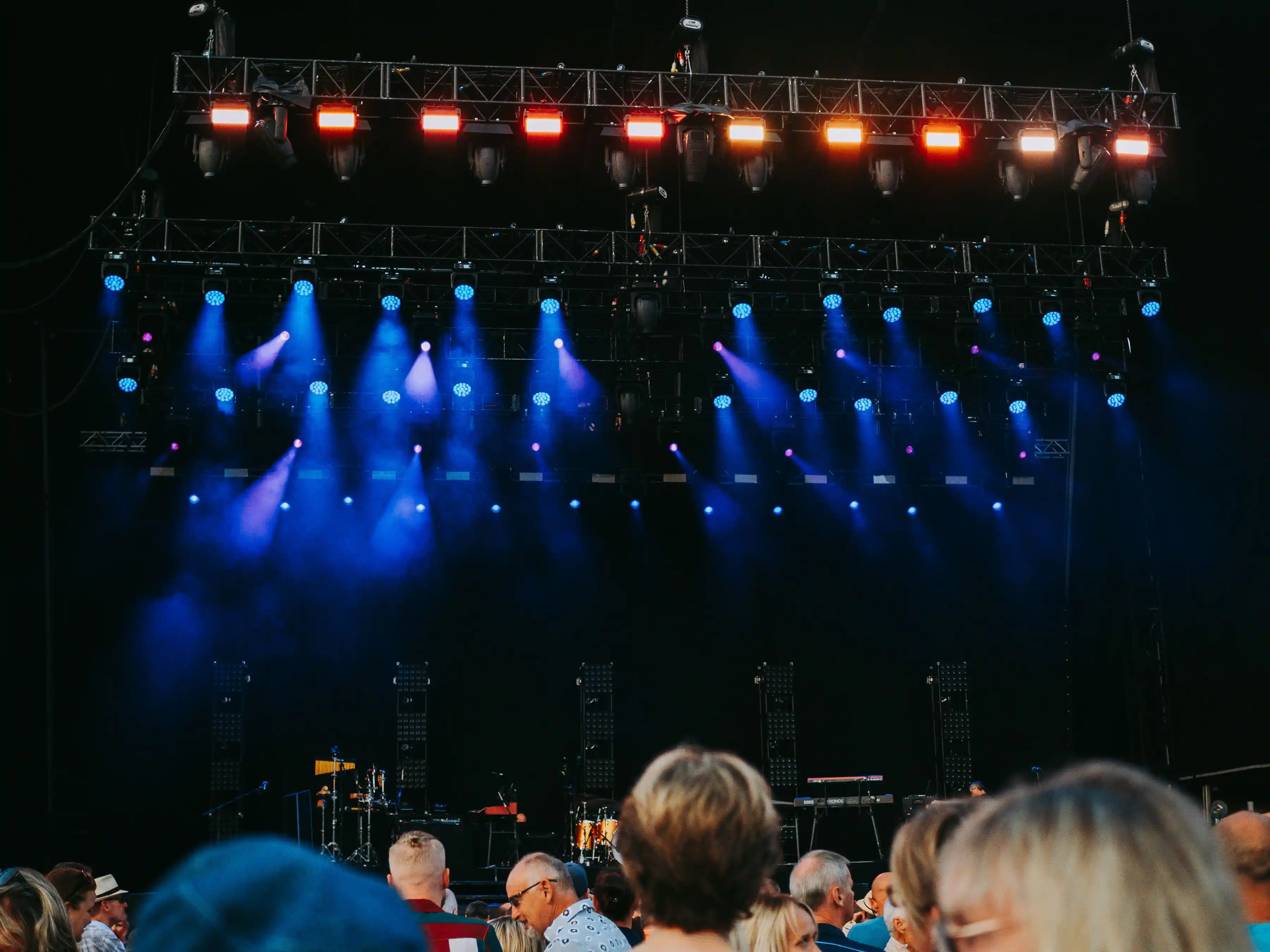 A night concert seen from the back of the crowd, the stage lit in blue and white