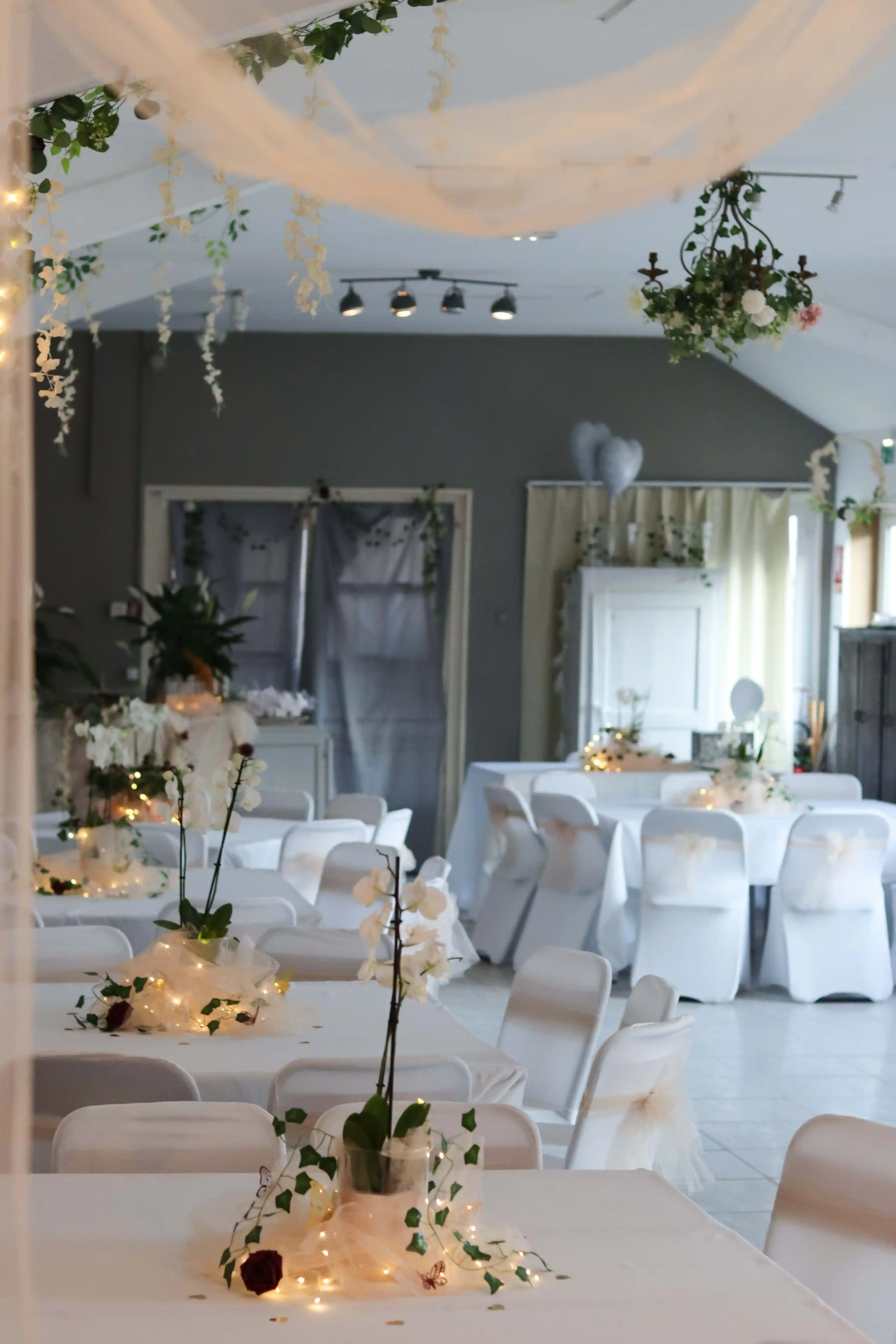 An indoor wedding floor with floral arrangements and pendant lighting overhead