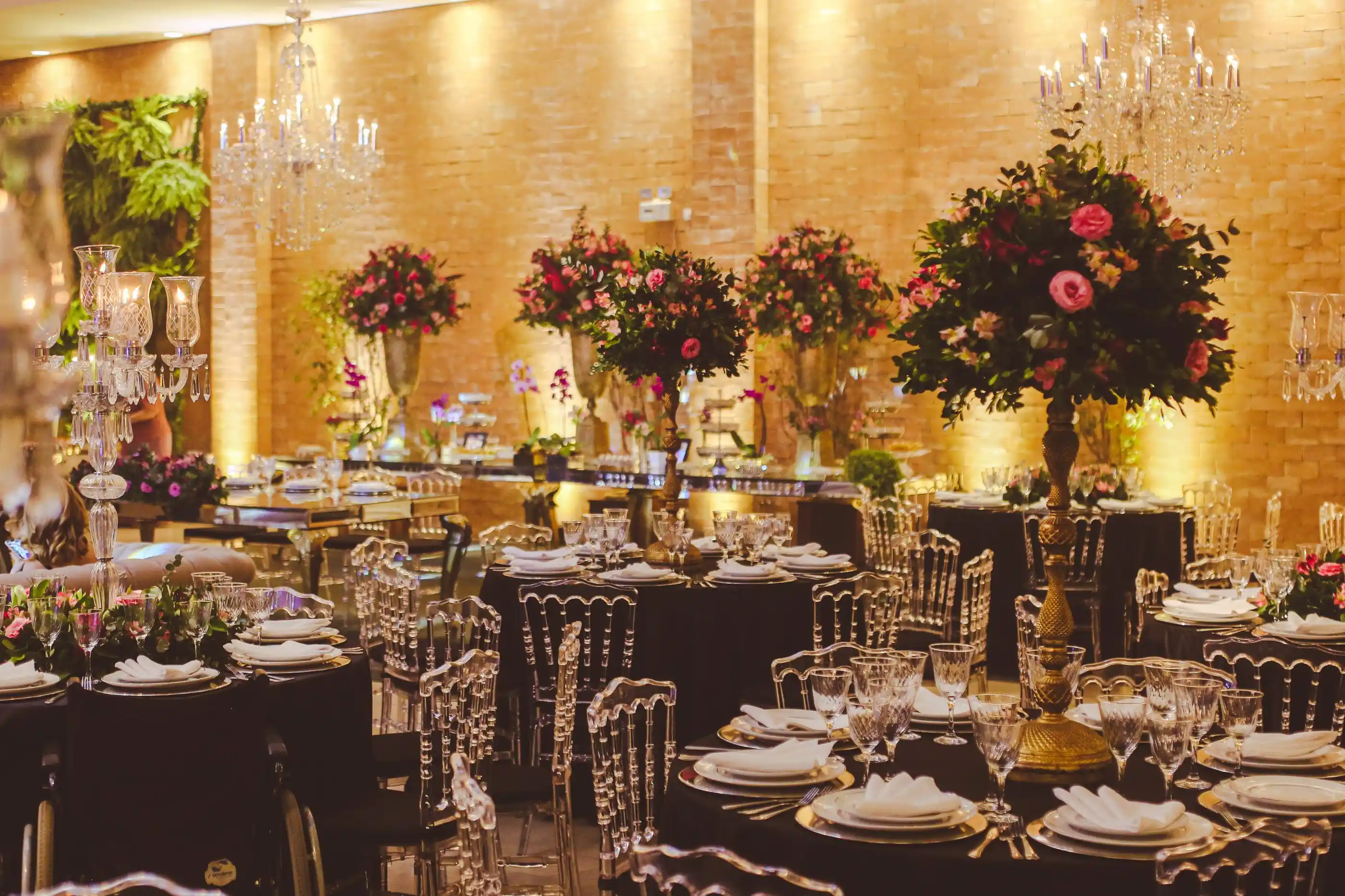 A ballroom floor with tall arrangements and crystal above every table