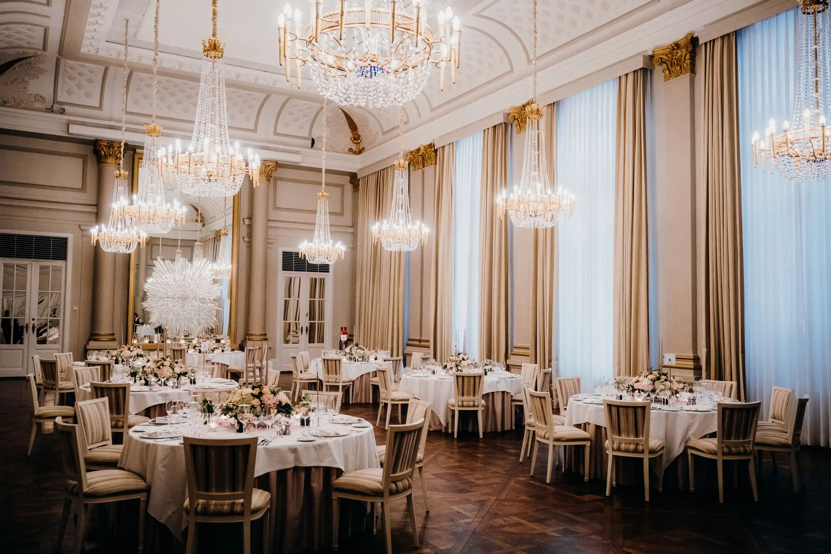 An elegant ballroom with chandeliers and tables set for dinner