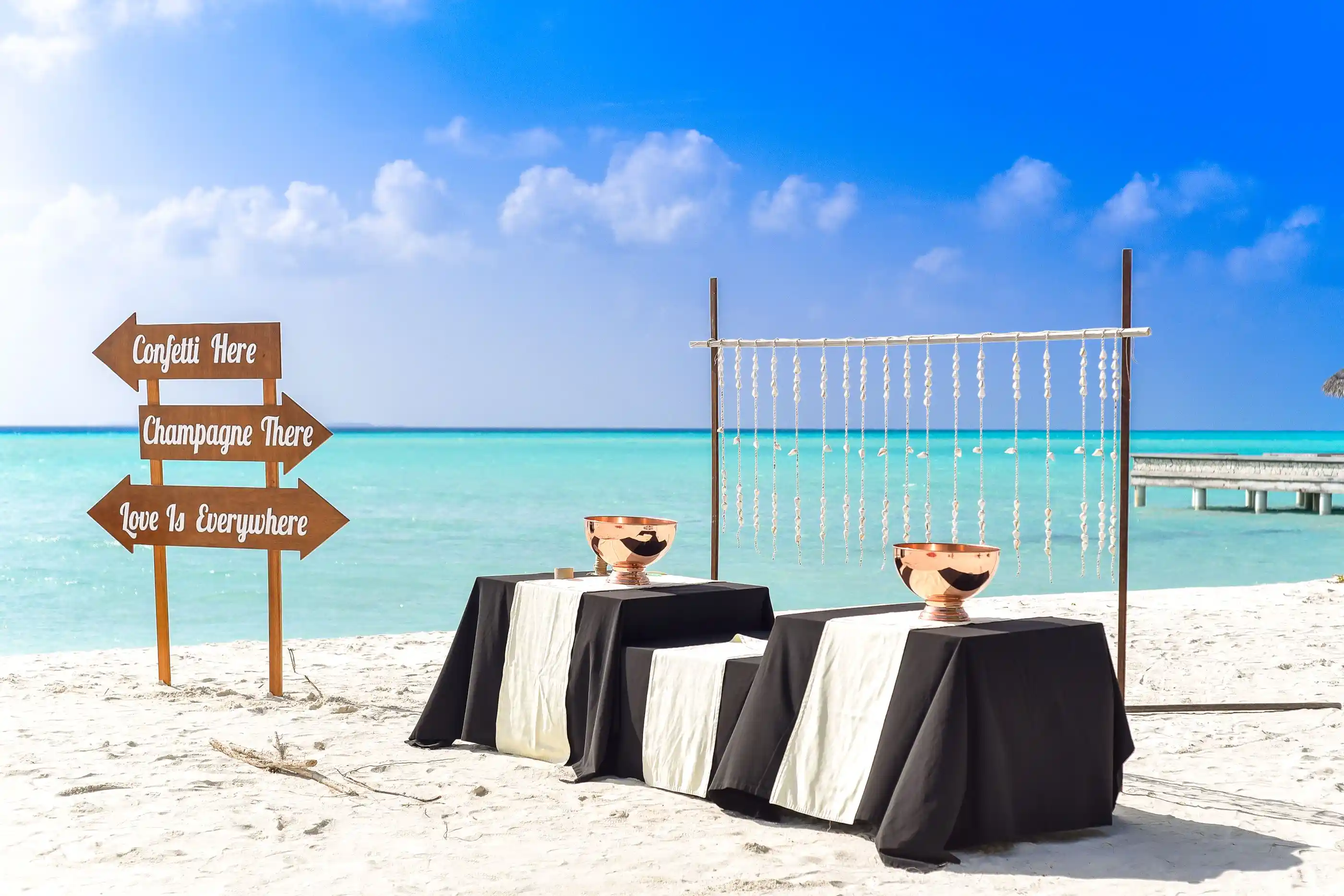 Tables laid on the sand with champagne waiting in the shade