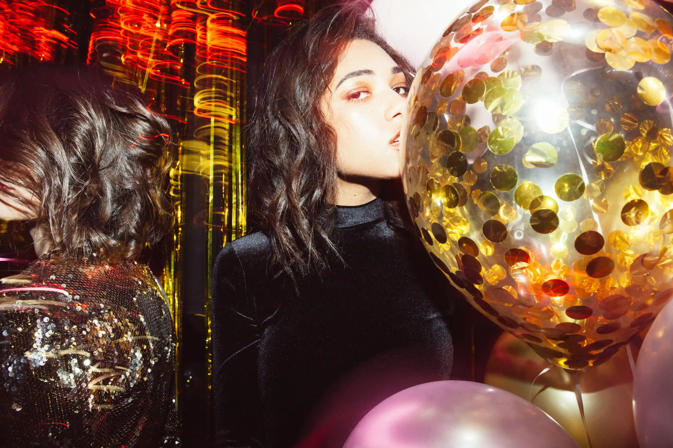 A guest in evening dress amid gold confetti balloons