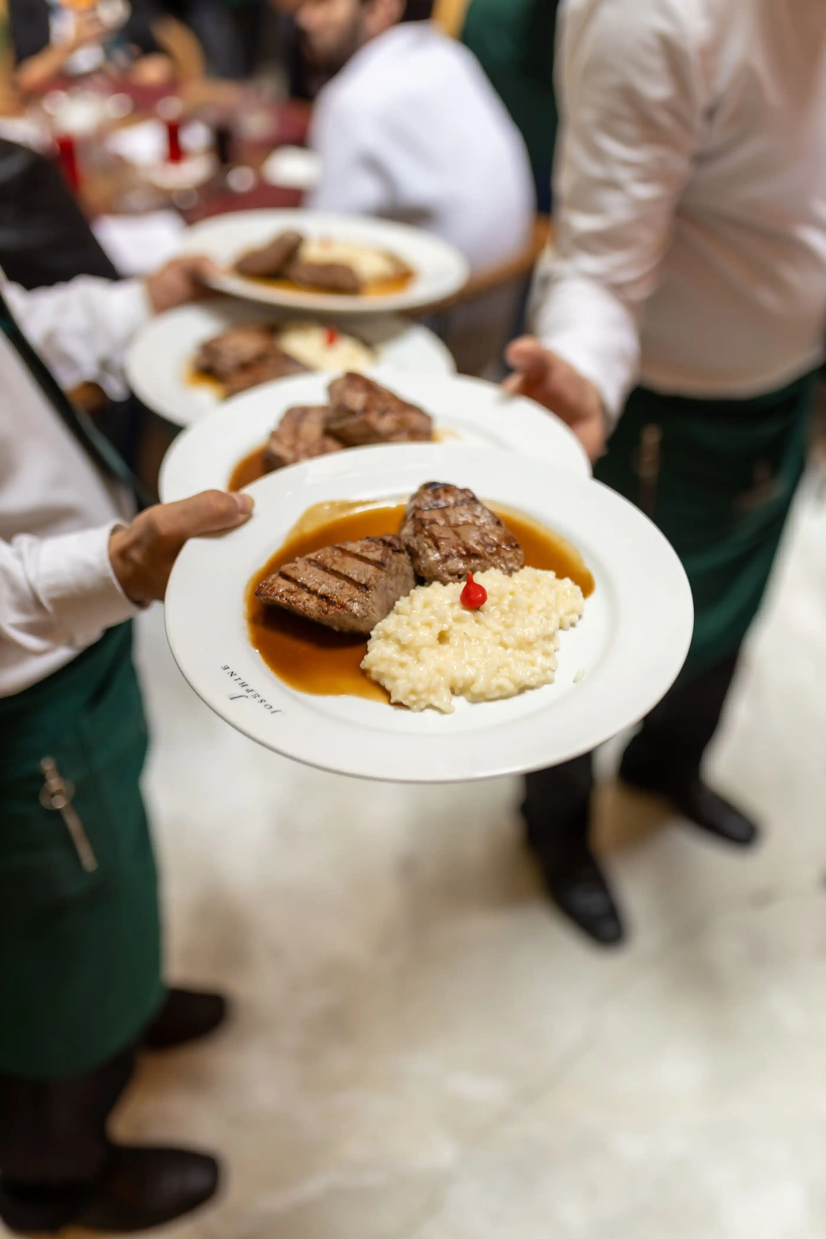 A server carrying plated main courses through a dining room