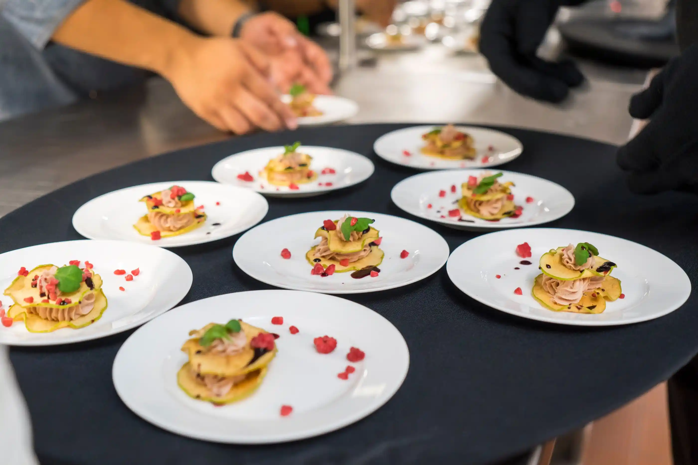 Appetiser plates lined up on a dark counter before service