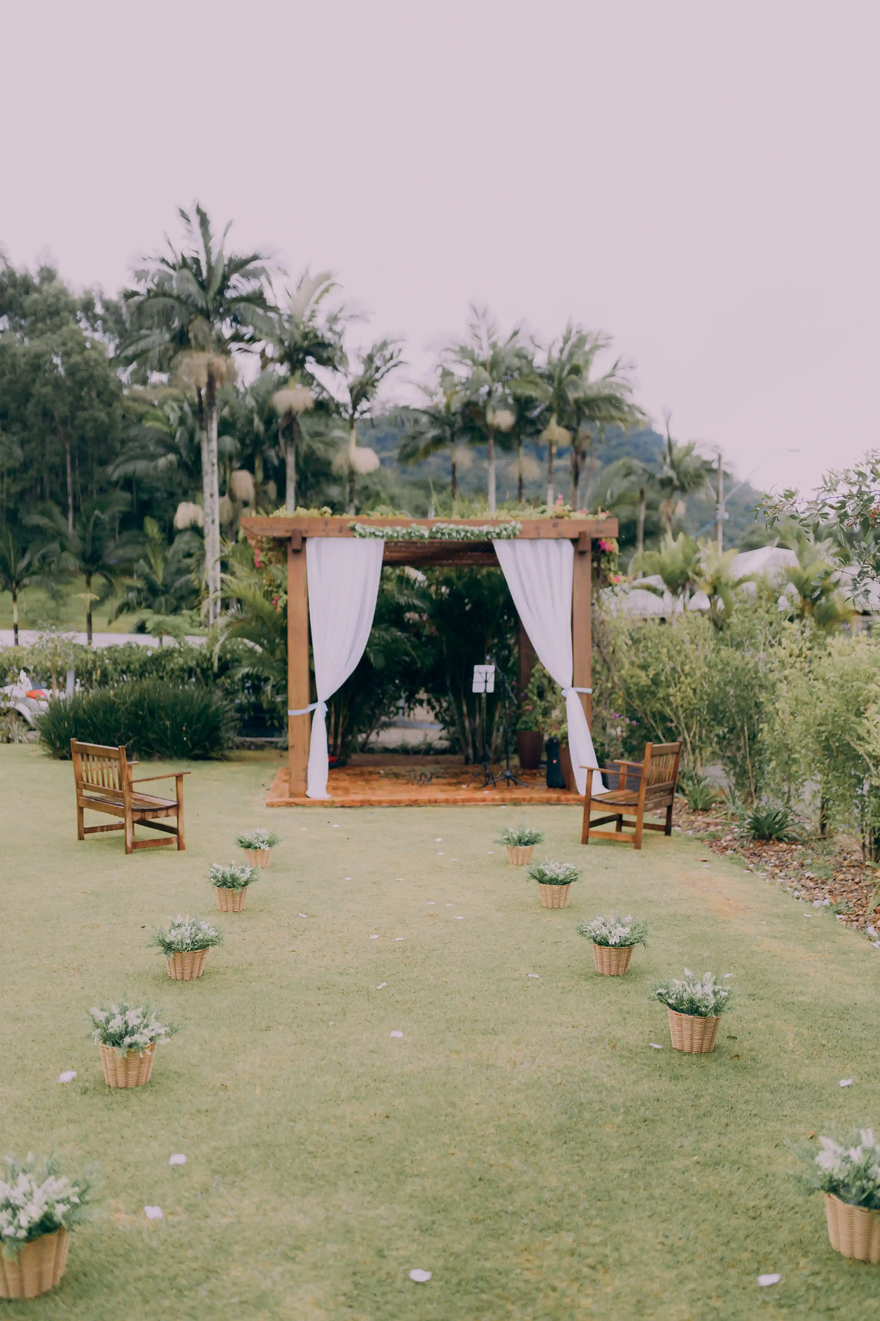 A garden ceremony with a wooden arch, flowers and open lawn seating
