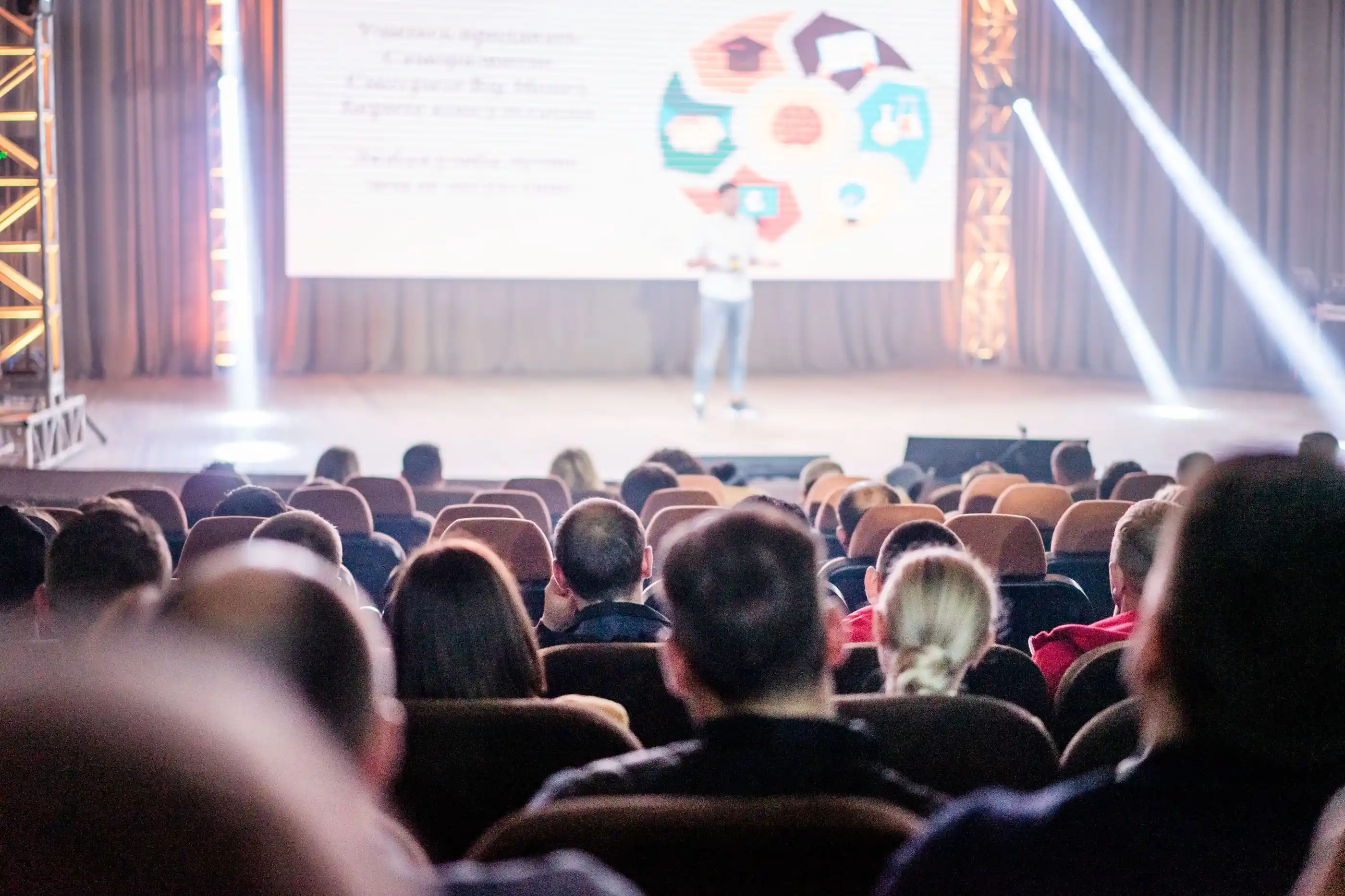 Delegates watching a presentation, the screen glowing at the front of the room