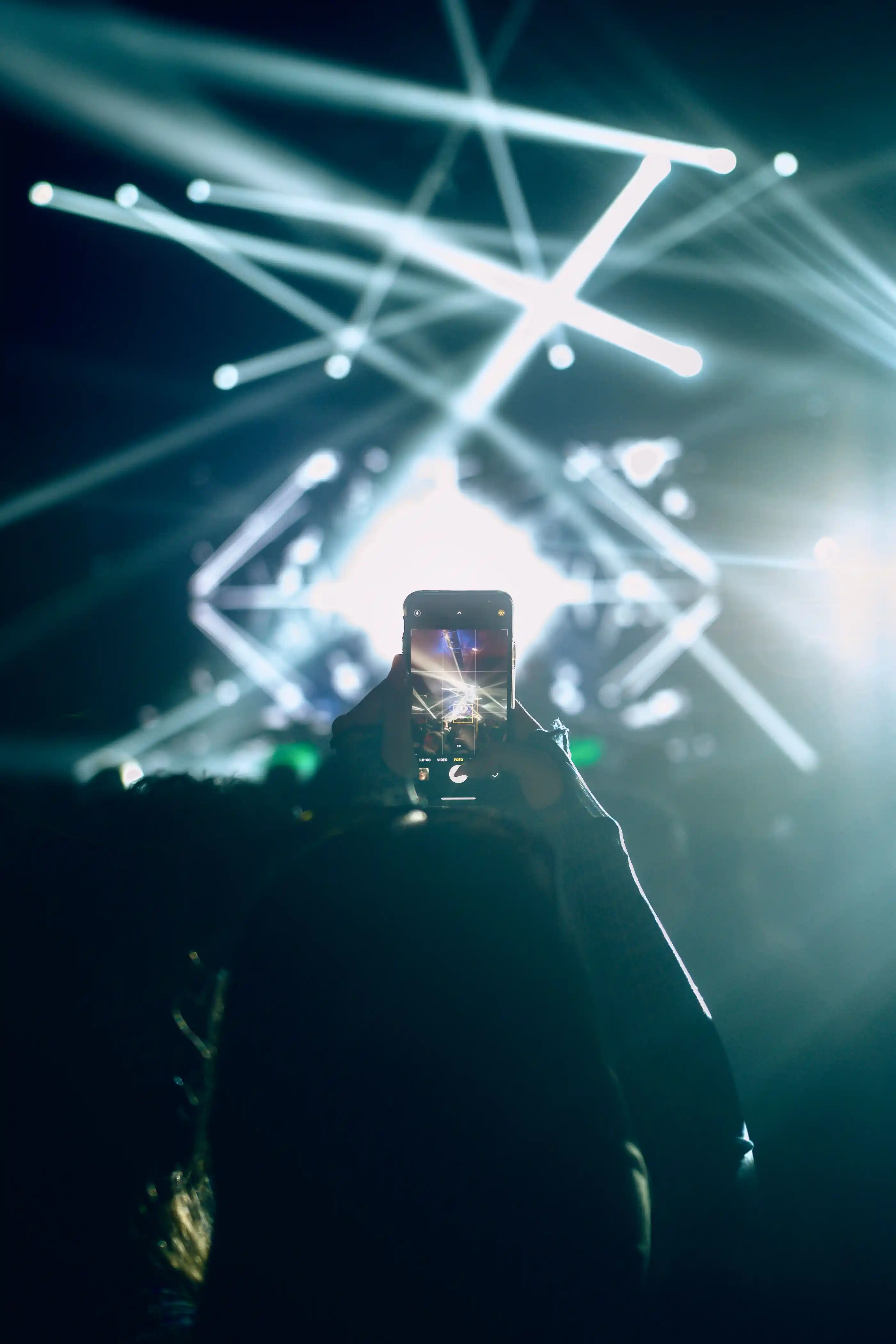 Streaks of light across a dark room as a crowd films the stage