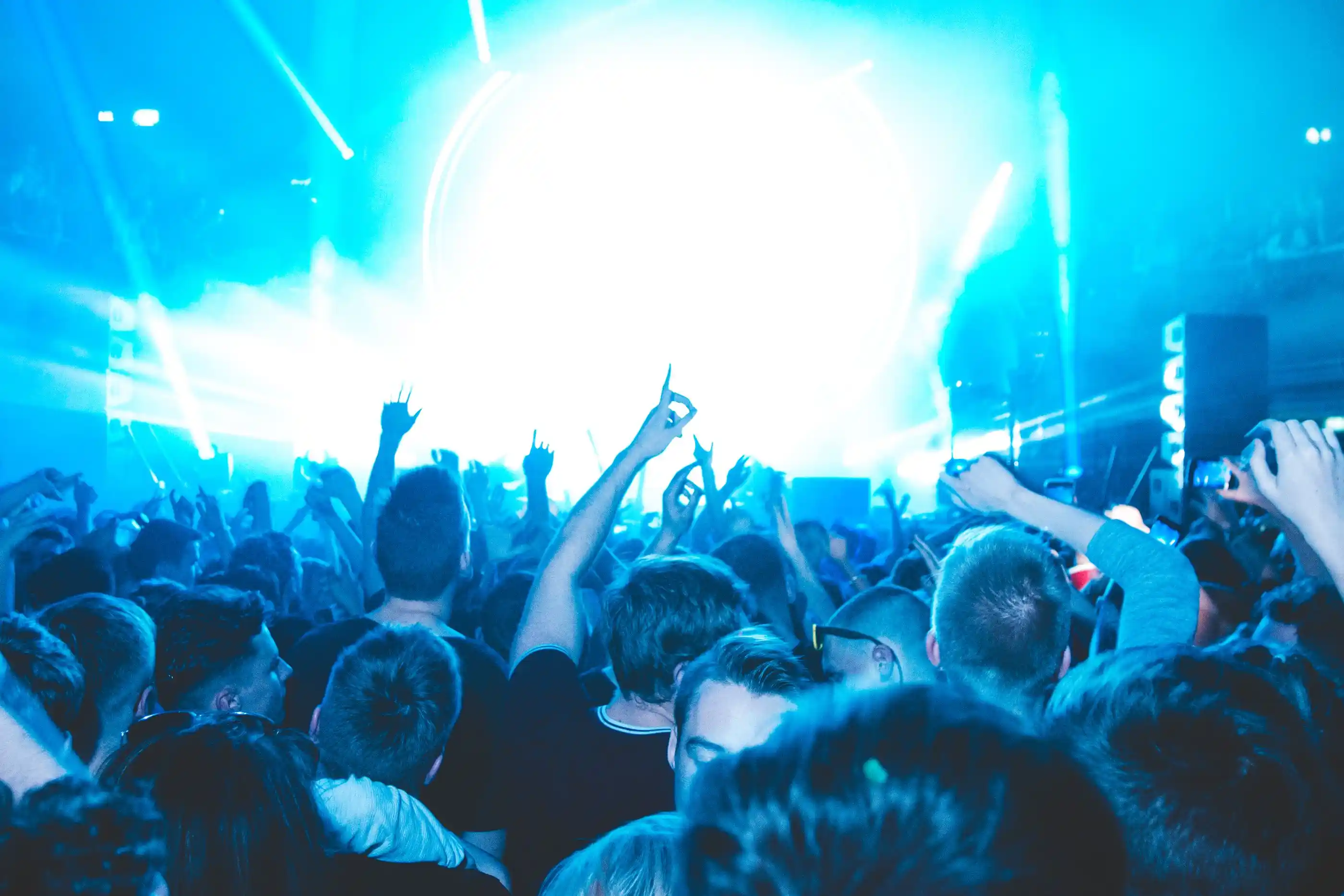 Hands raised in a crowd against a wall of white light