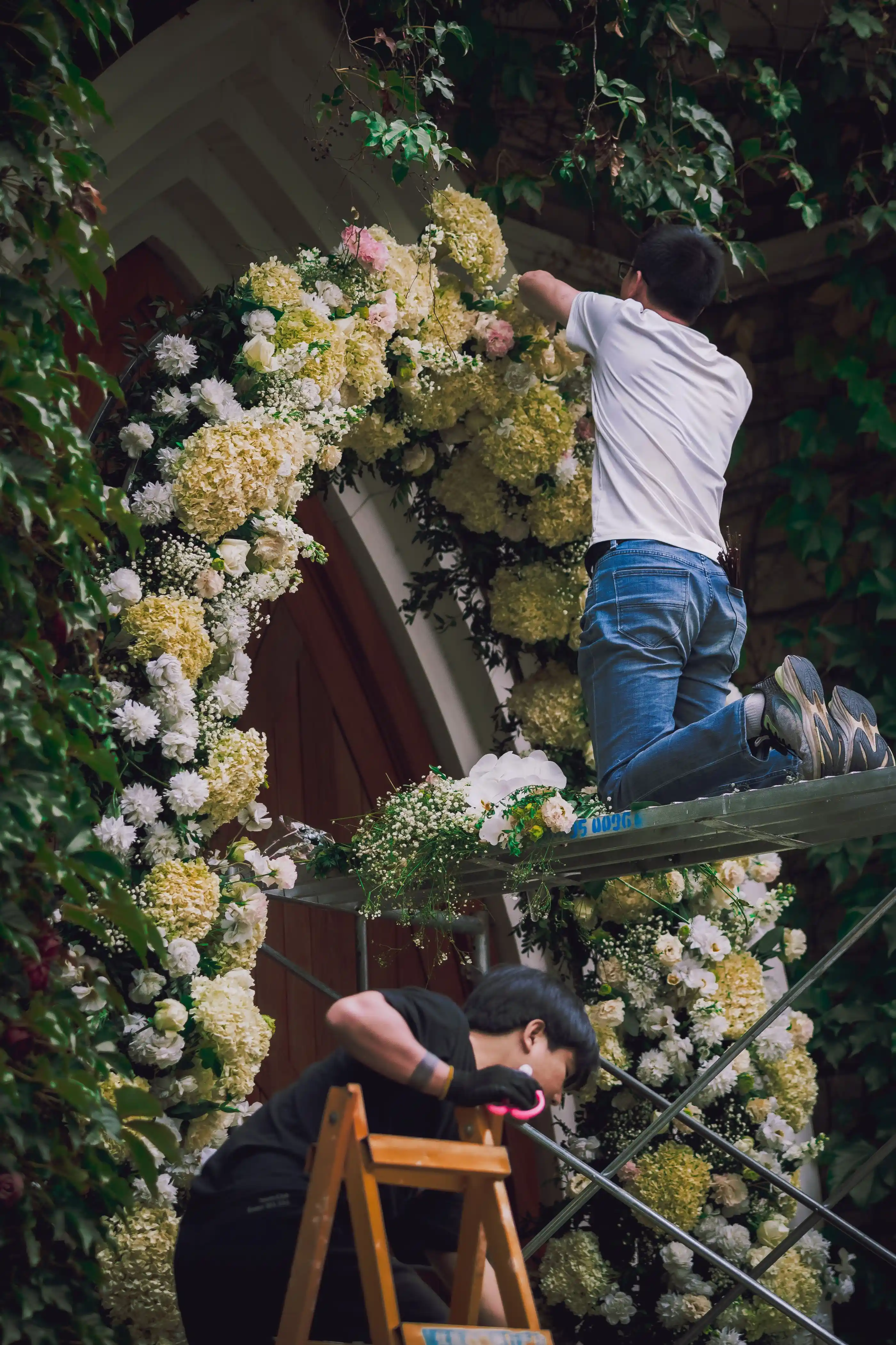 Two florists building a flower arch on site