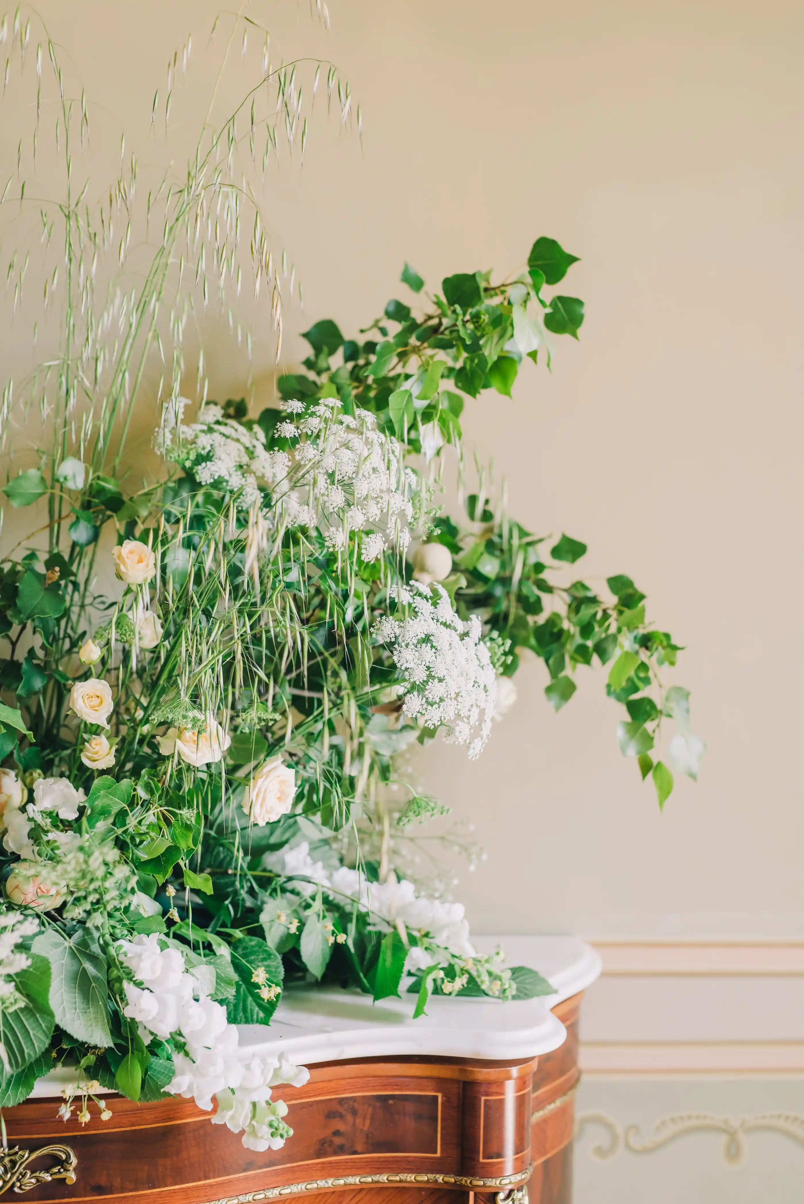 A white and green arrangement with trailing foliage