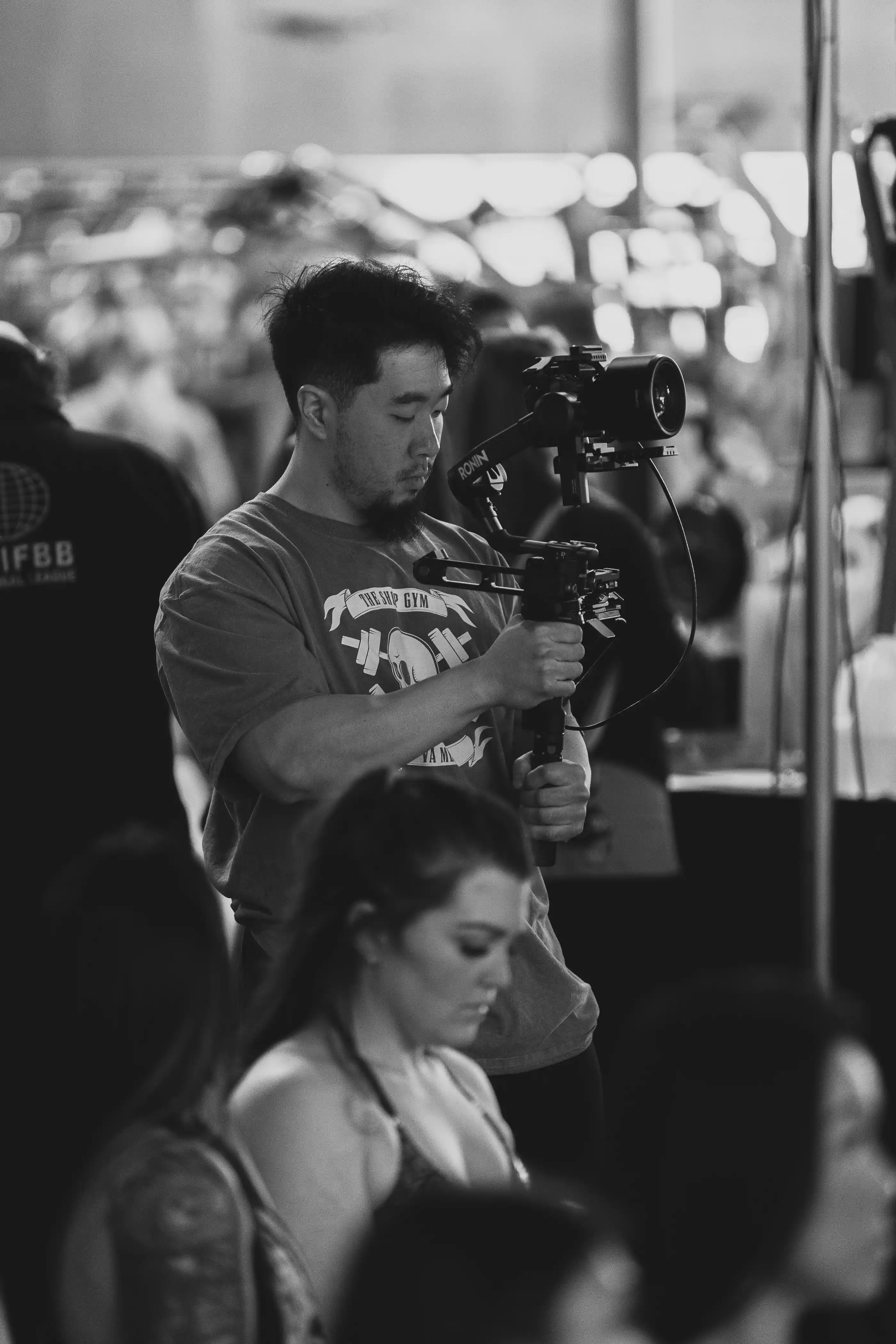 A camera operator filming a live performance in black and white