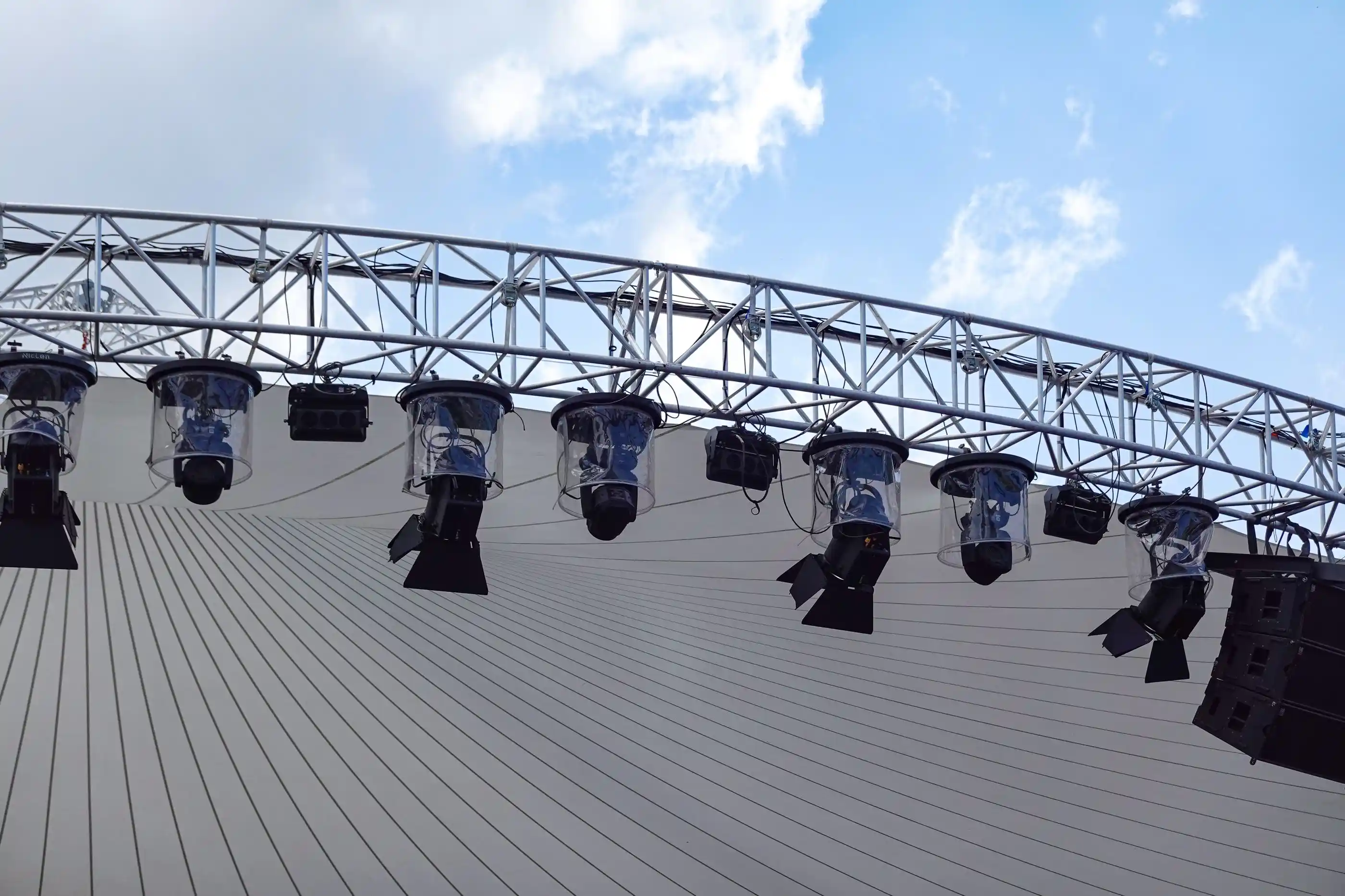An outdoor lighting truss loaded with fixtures against a clear sky