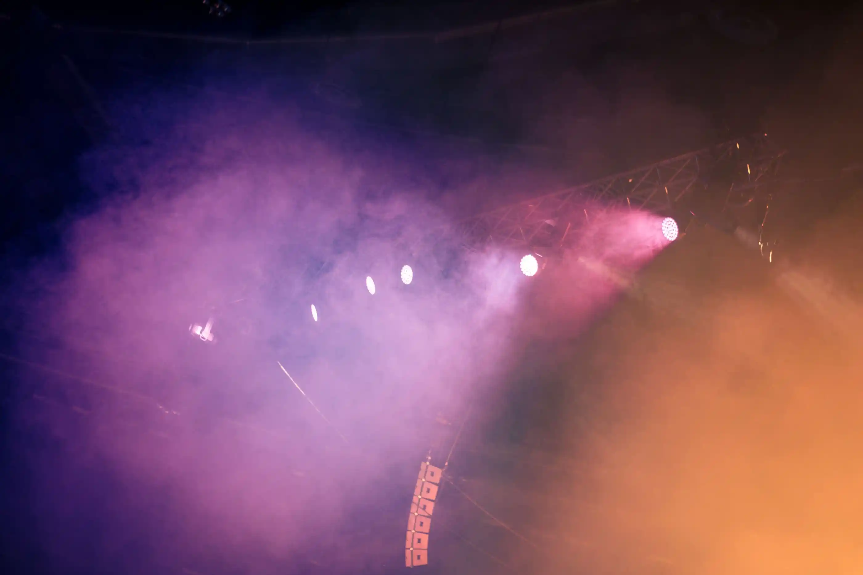 Coloured stage lighting and low fog across an empty performance space