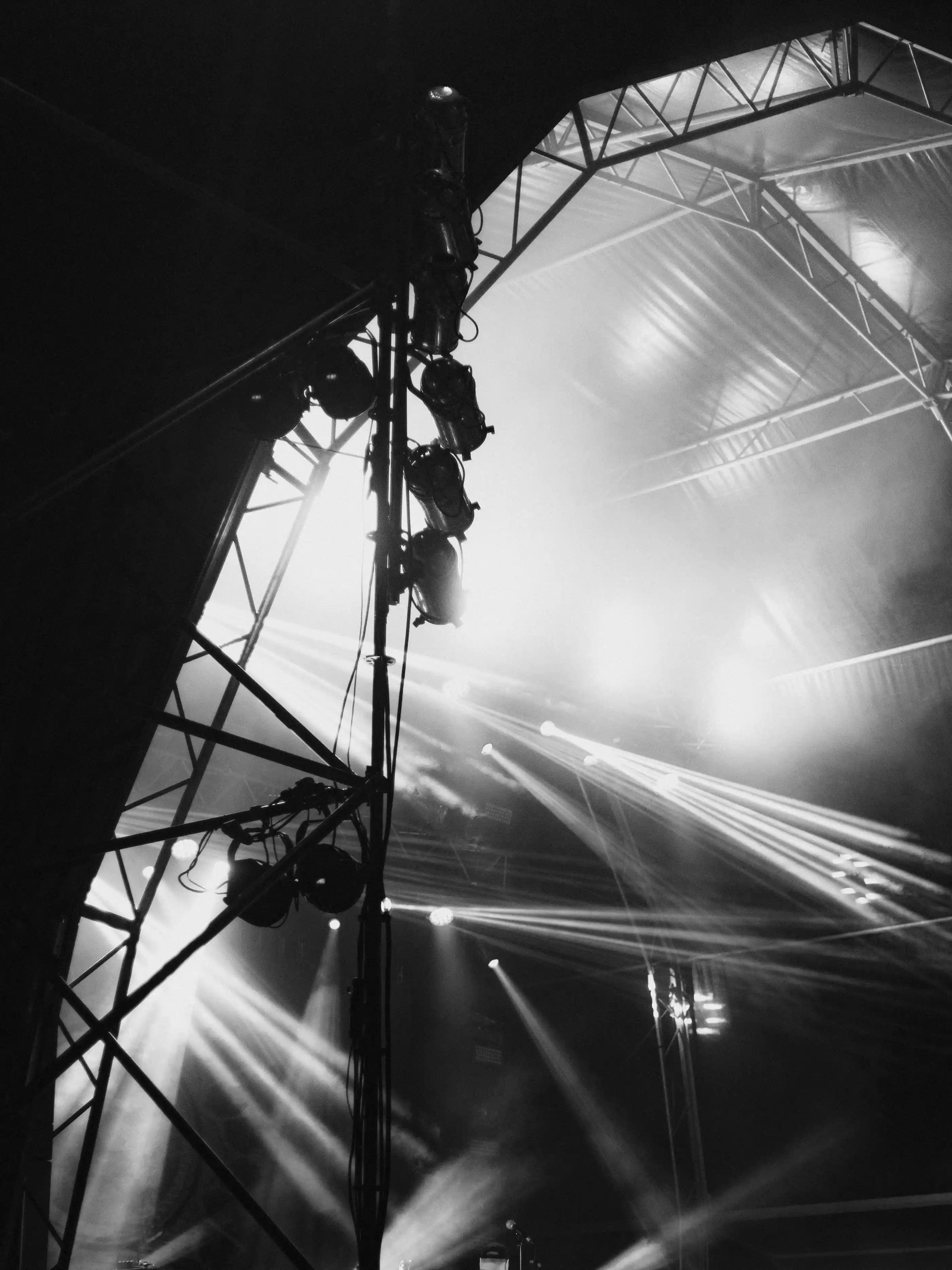 A monochrome frame of a concert stage rig seen from the floor