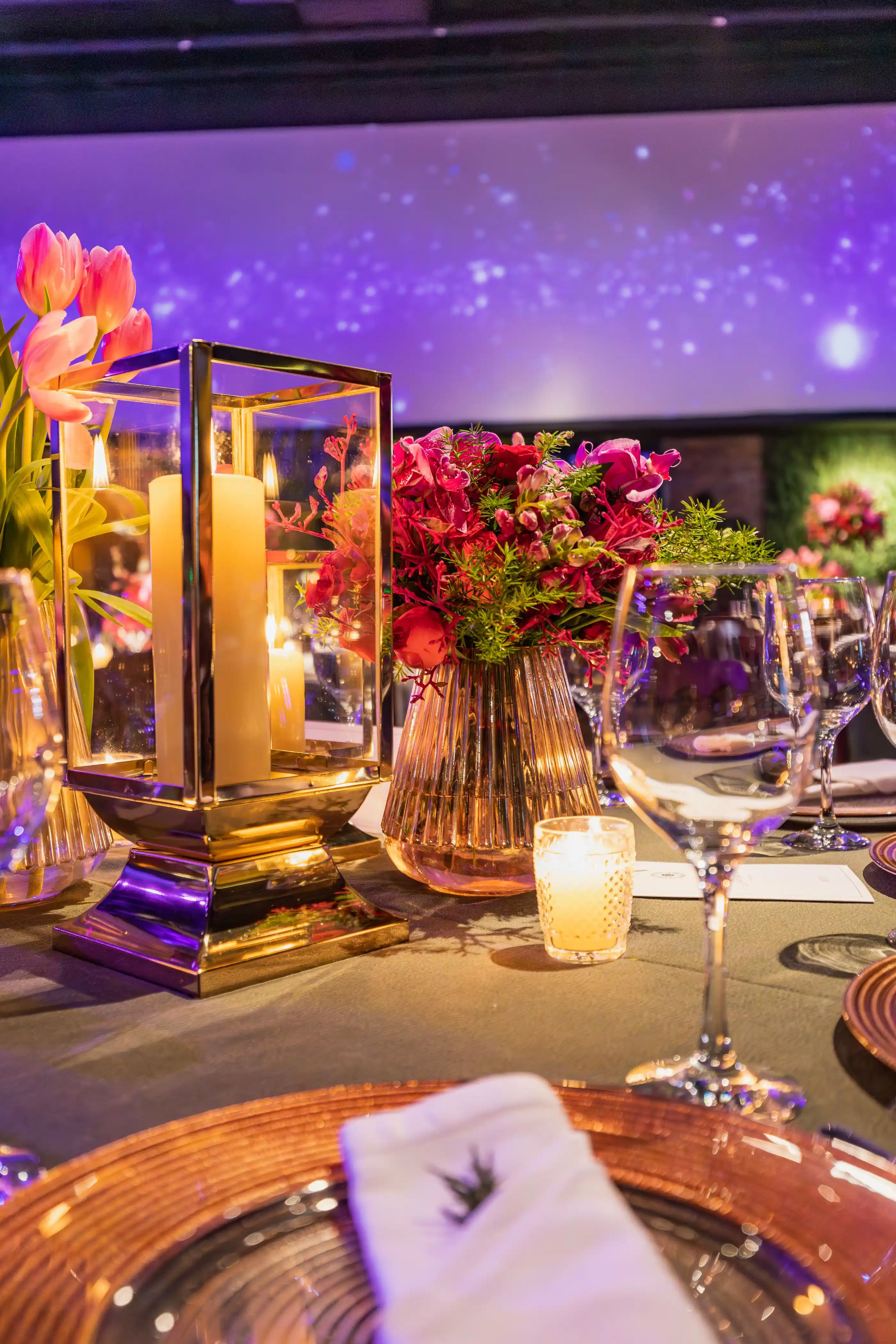 A place setting with a low floral centrepiece and lit candles