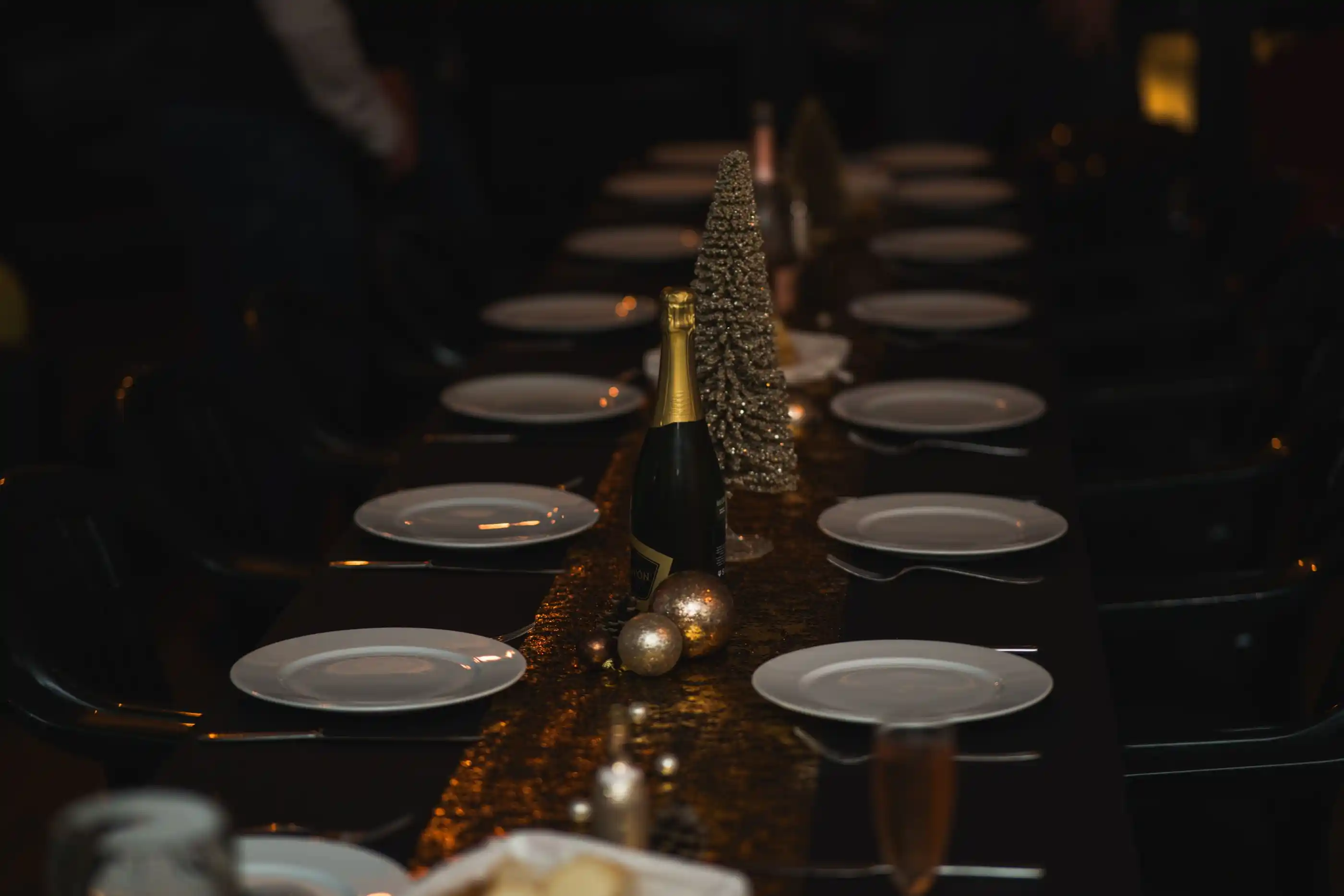 A long dark table set with plates and glassware, candles down the centre