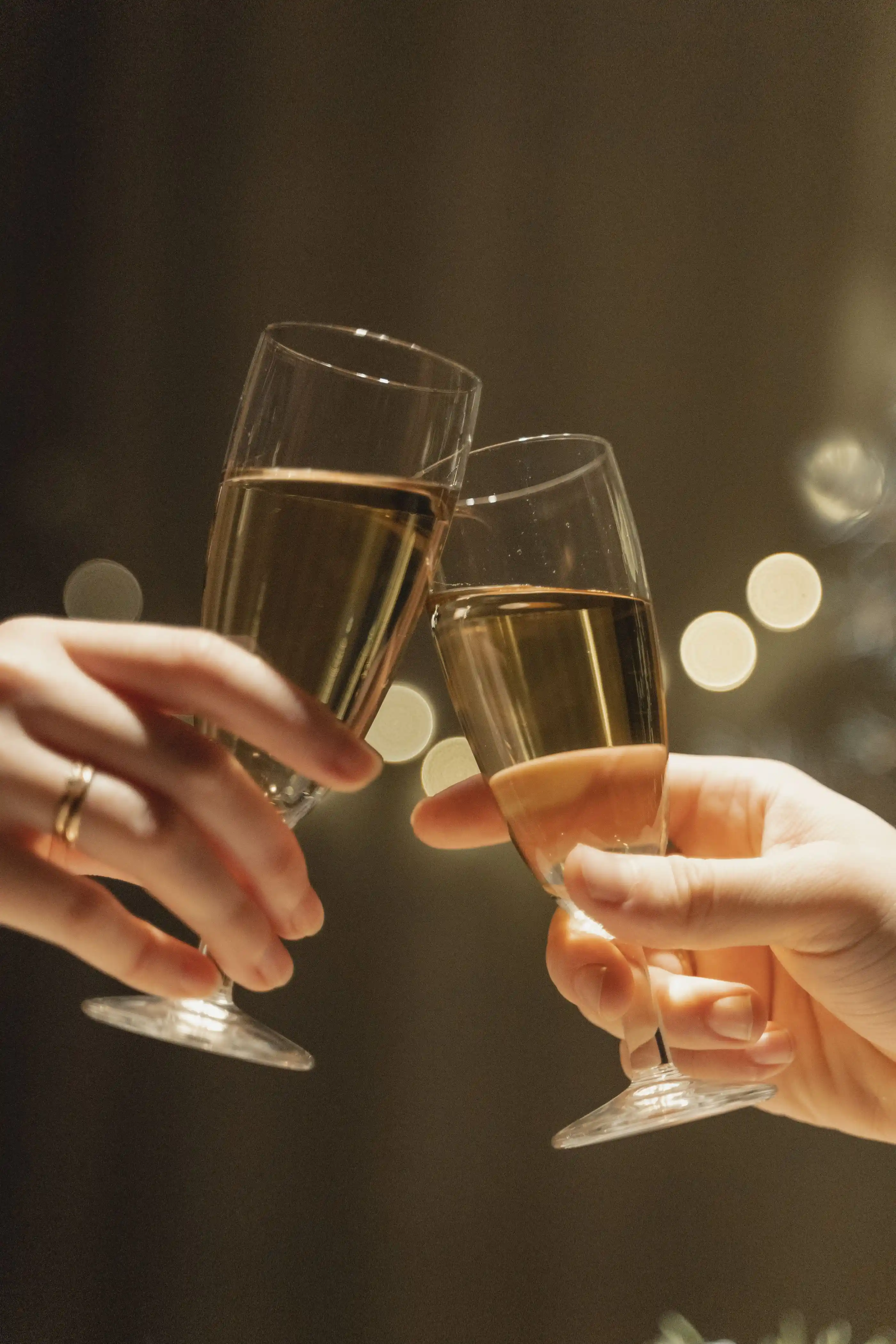 Two hands touching champagne glasses together