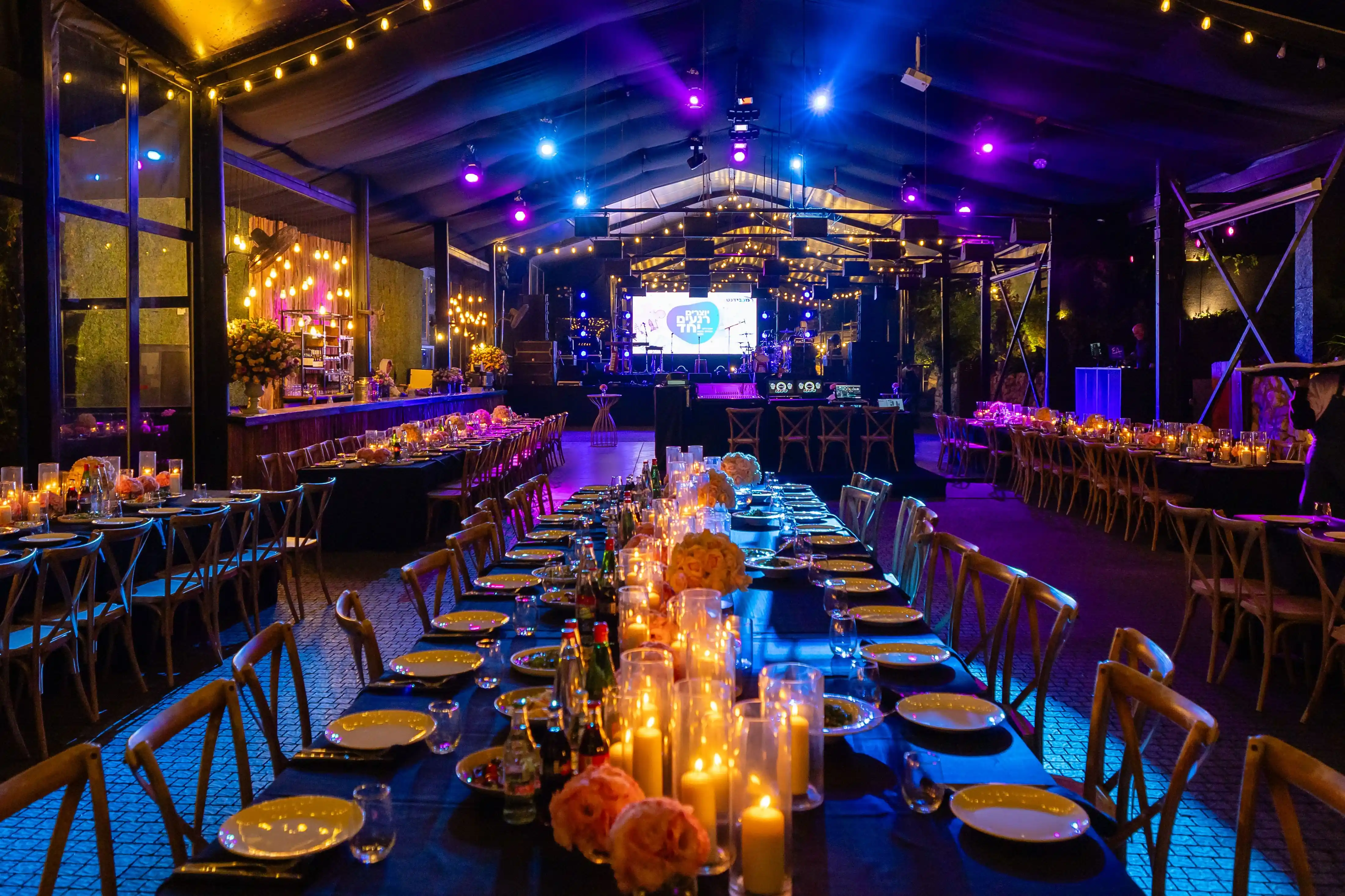 A long banquet table set for the evening, candles running its full length beneath low amber lighting