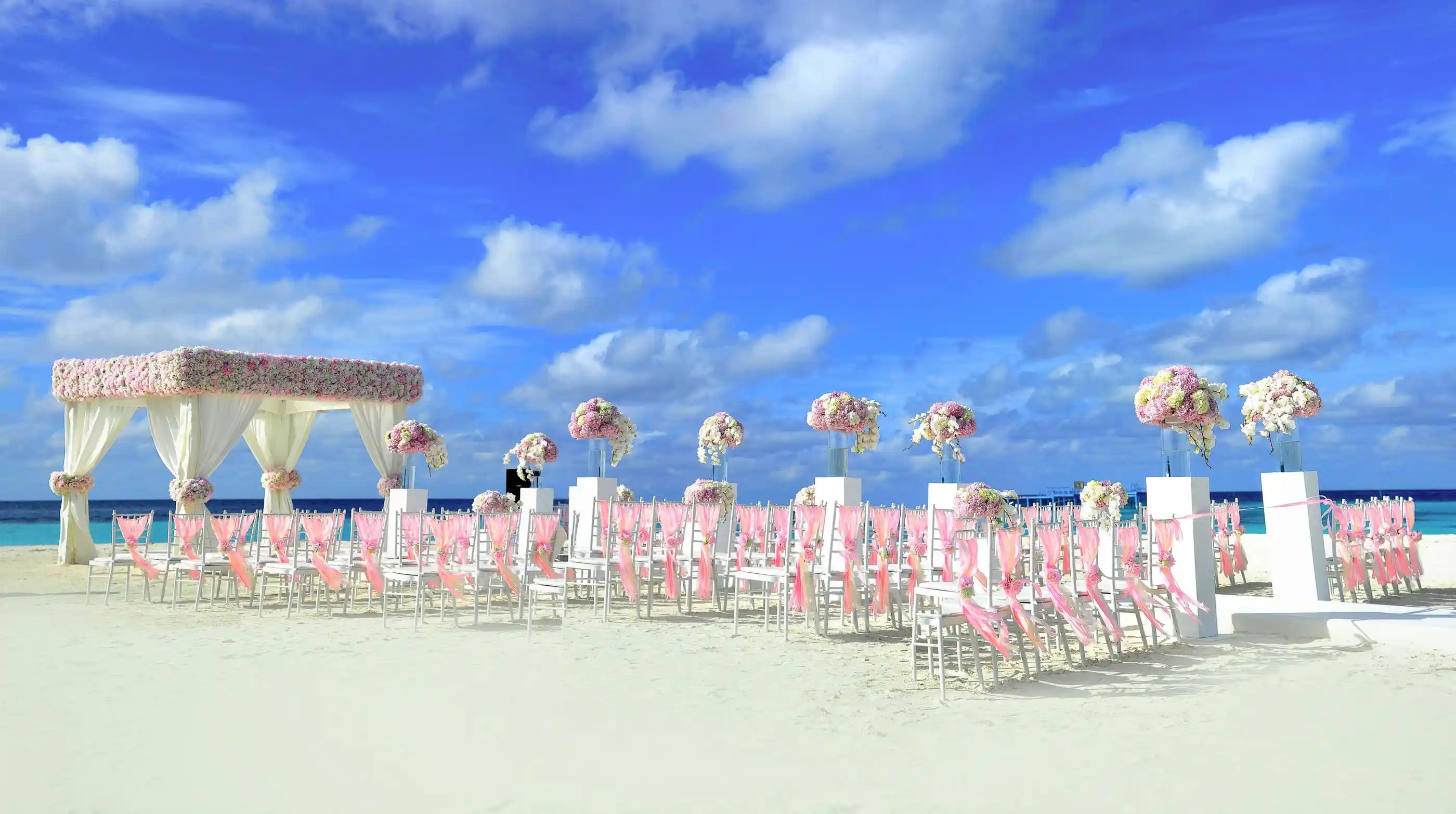 A ceremony set on a bright beach beneath a decorated canopy