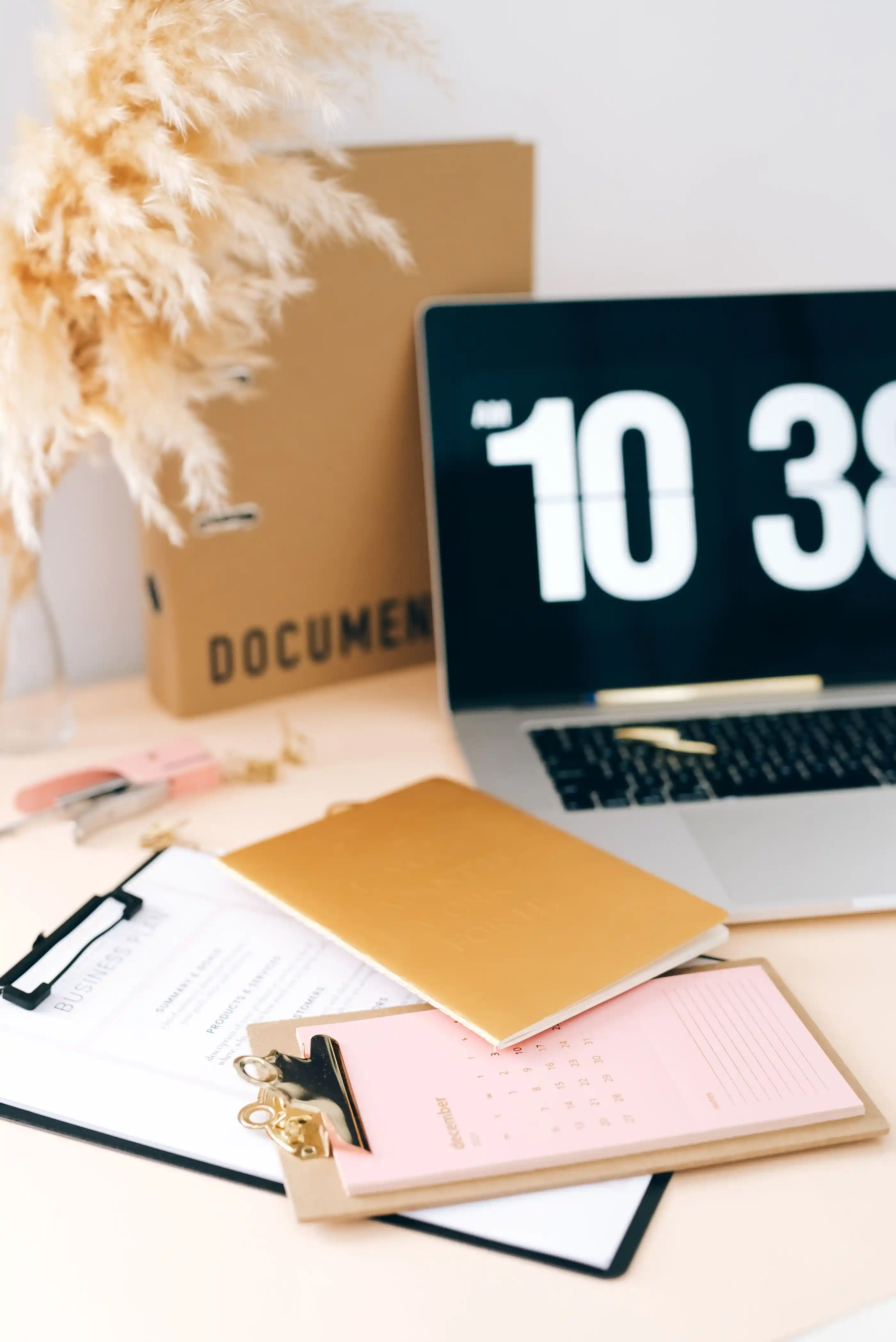 A desk with a laptop, clipboard and planning documents