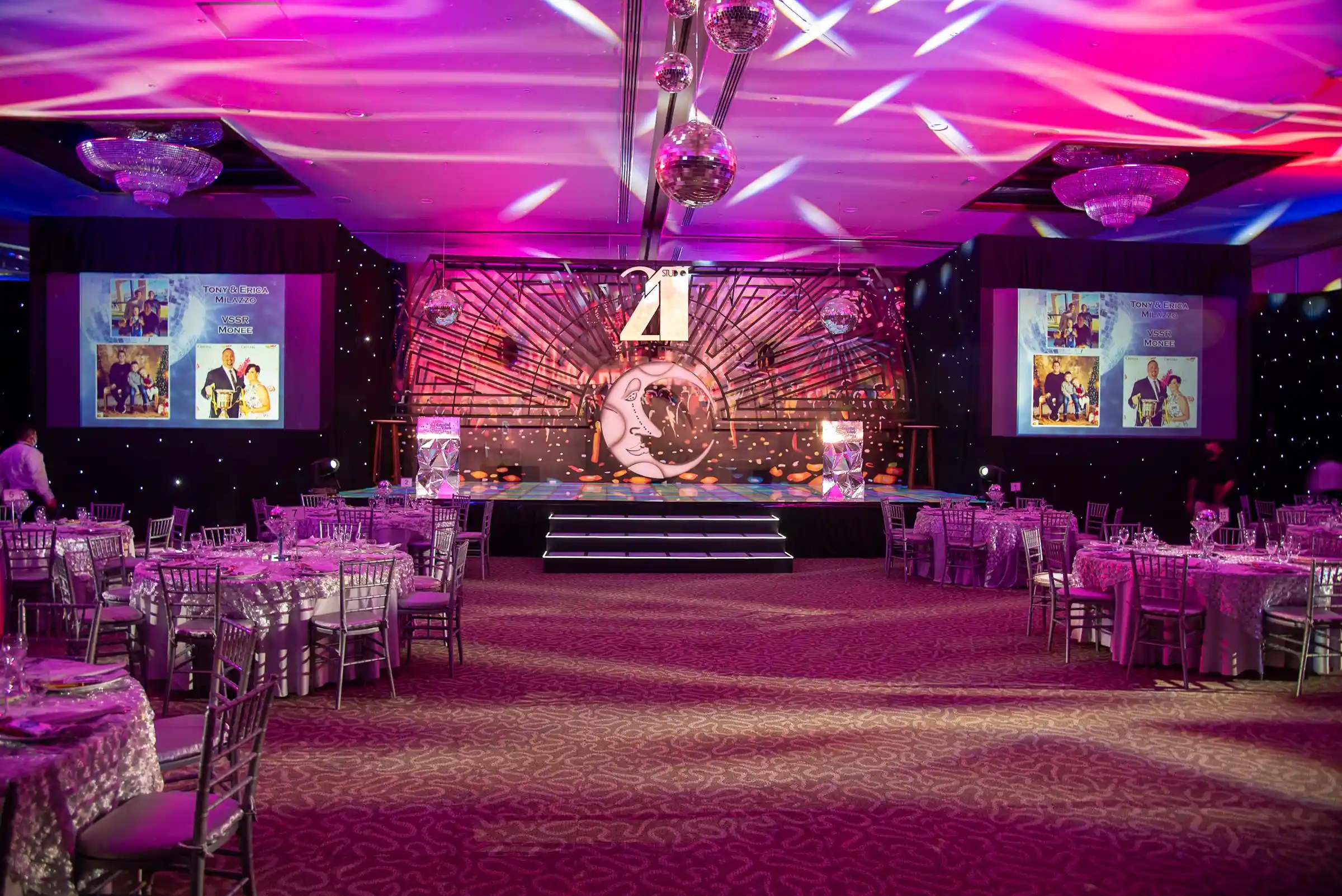 A themed event hall lit in magenta with a full stage build