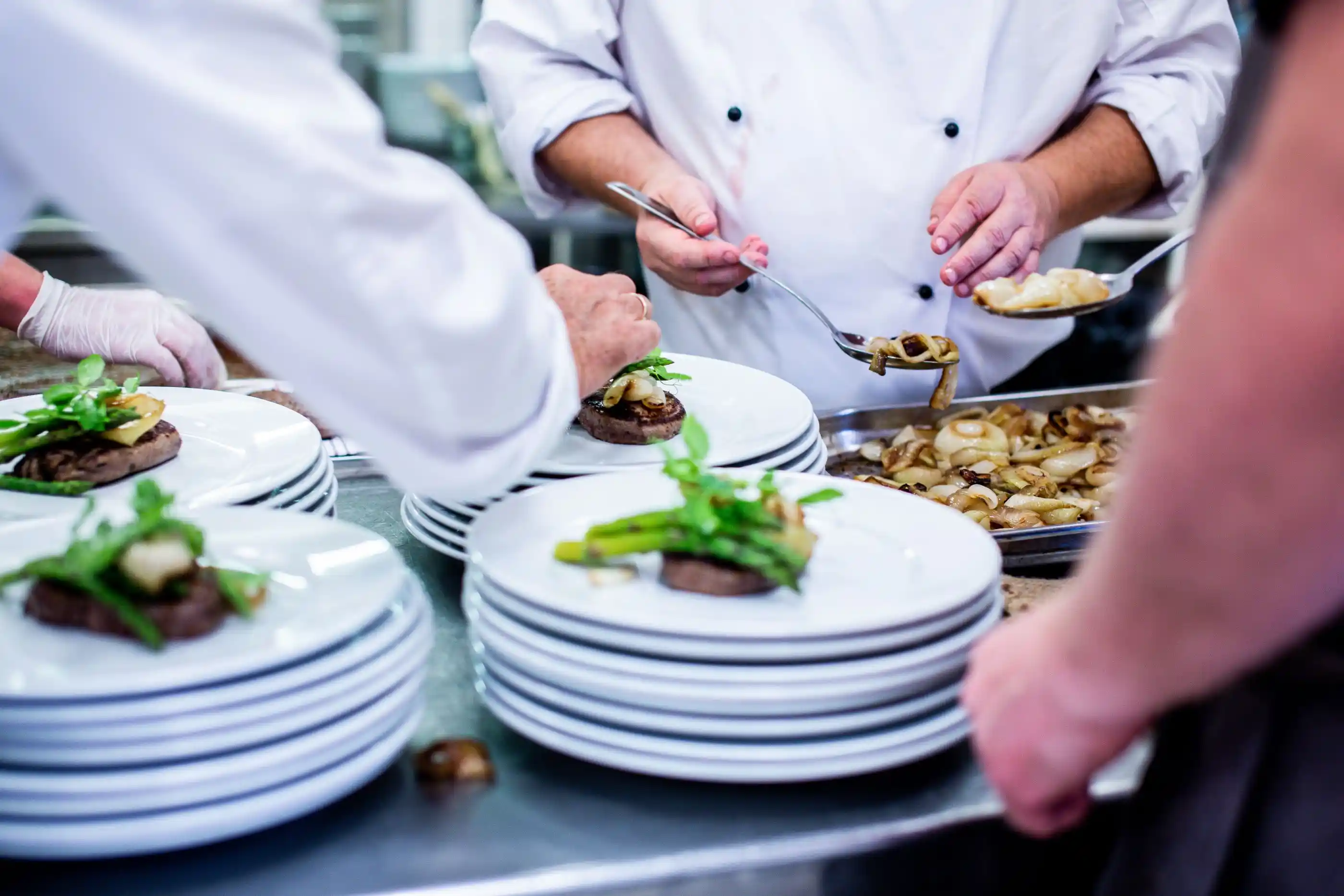 Chefs finishing plates side by side in a service kitchen
