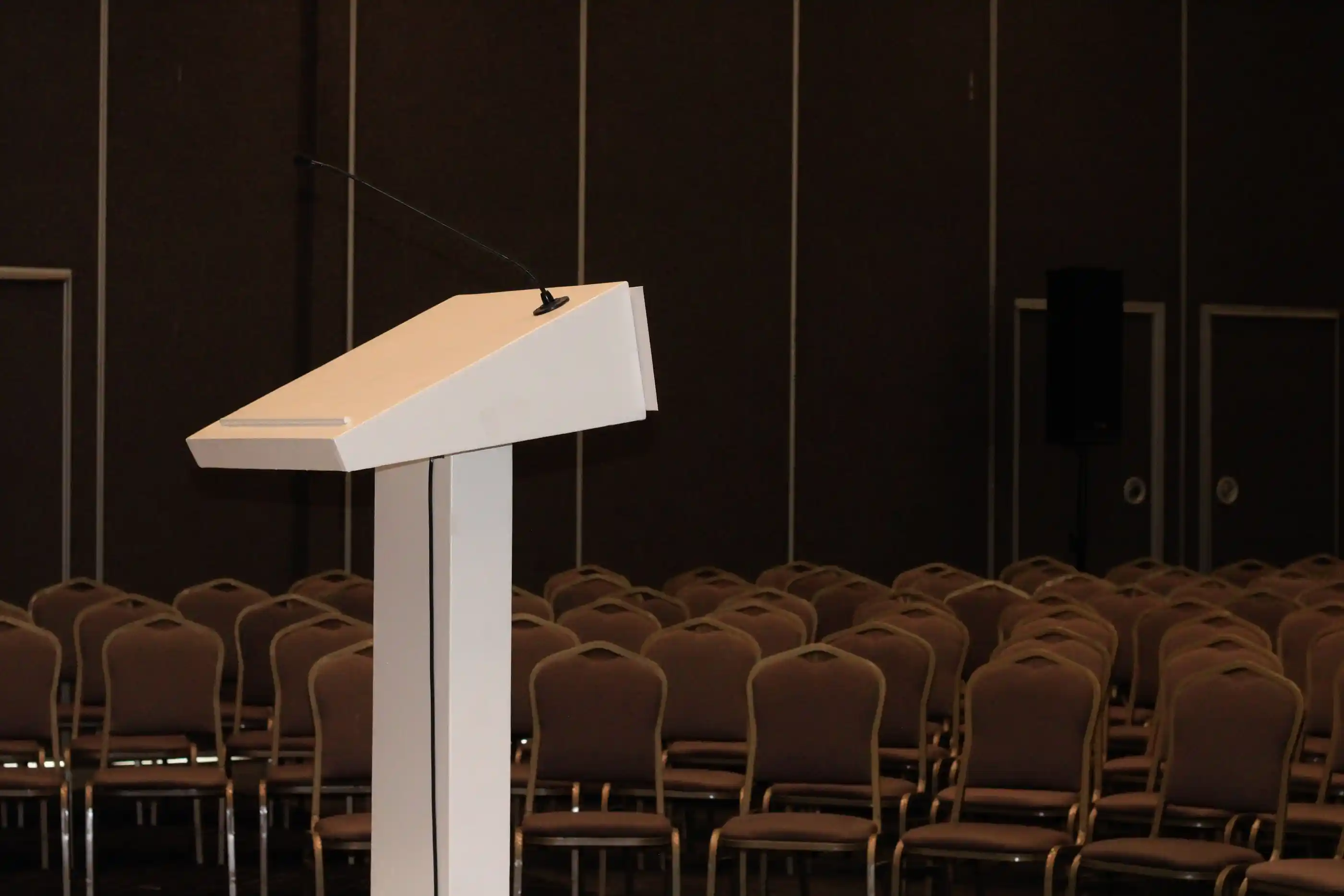 A conference room set with a lectern and rows of chairs before doors open