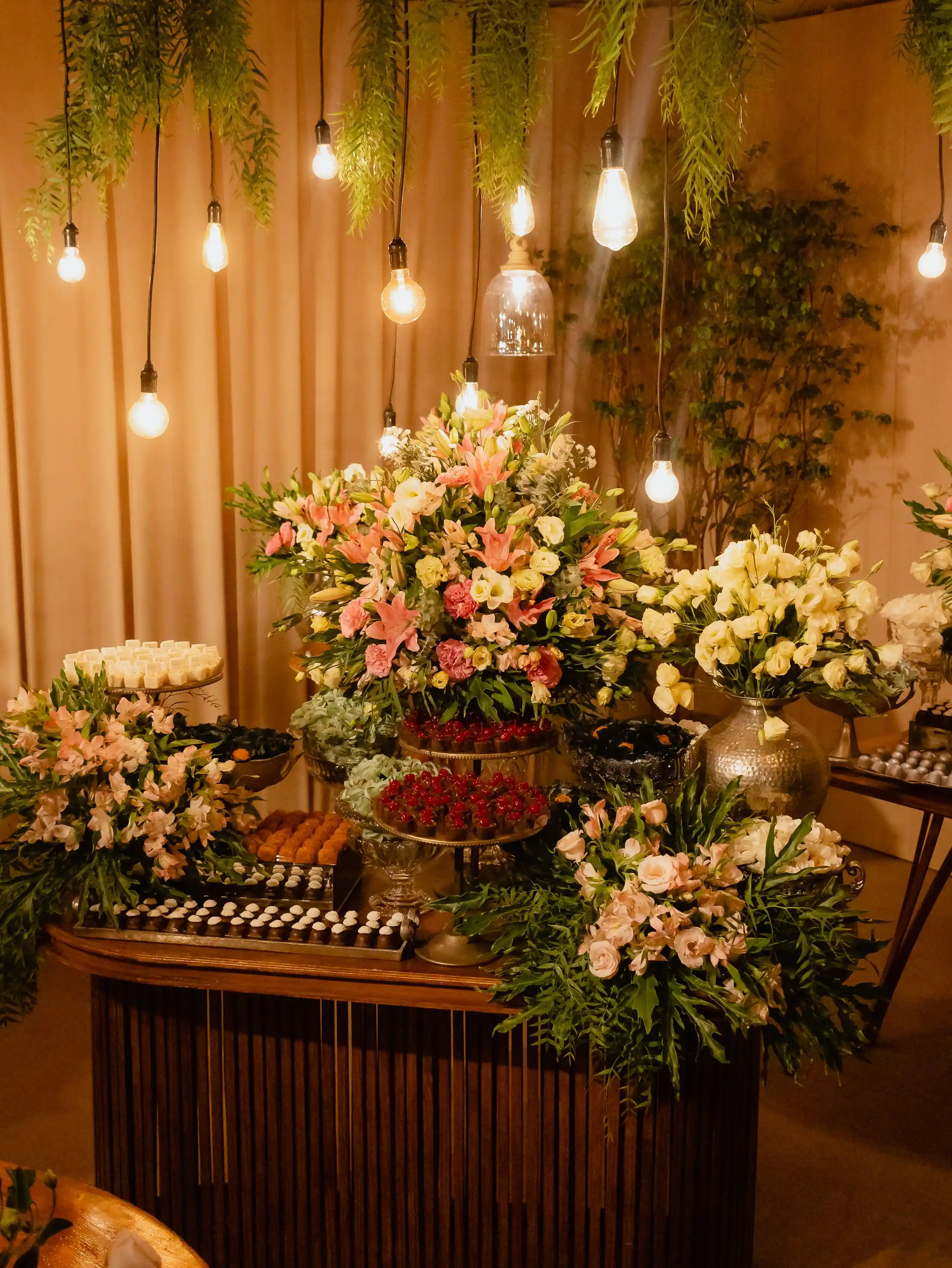 A suspended floral installation lit by hanging bulbs