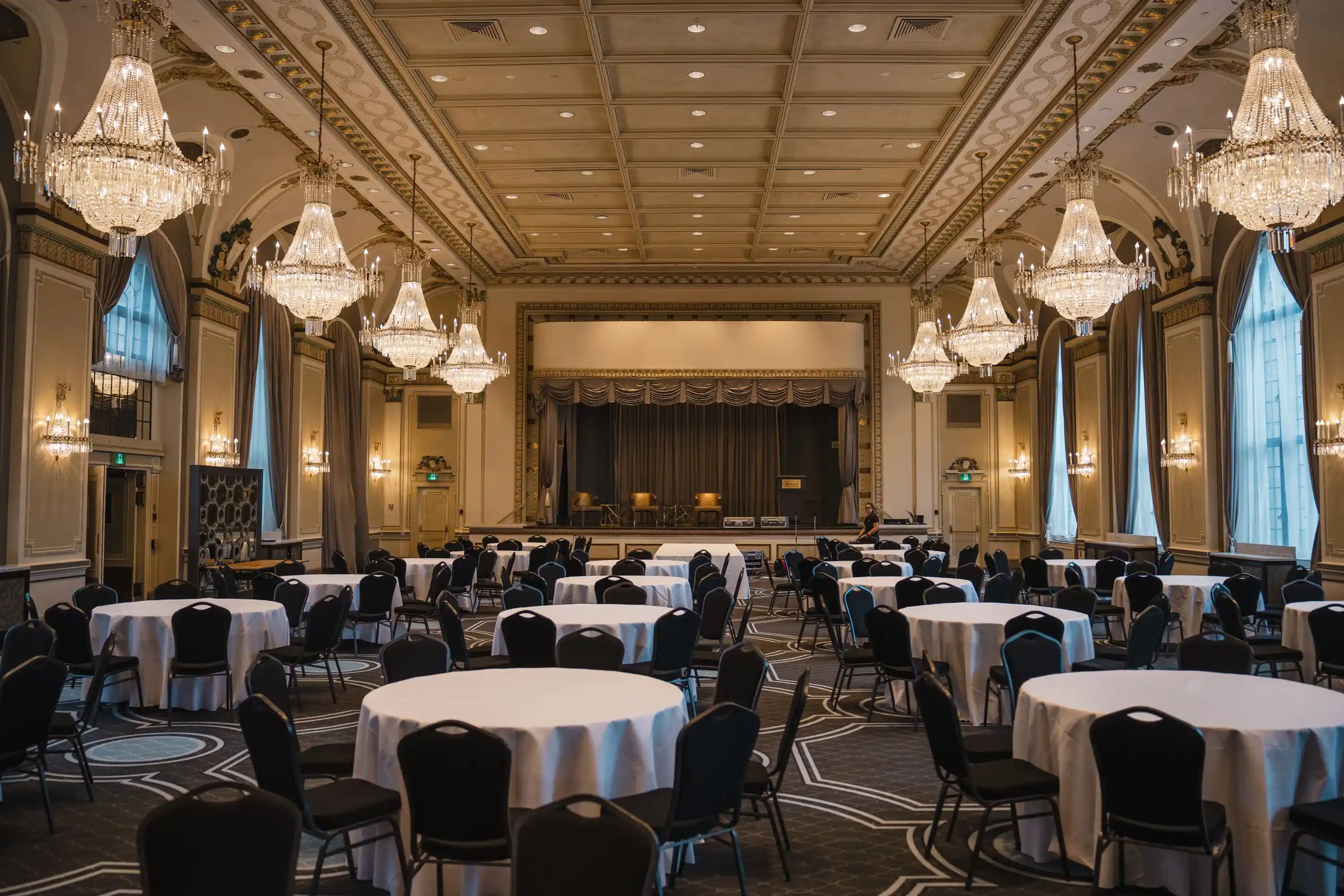 An empty banquet hall with round tables and chandeliers