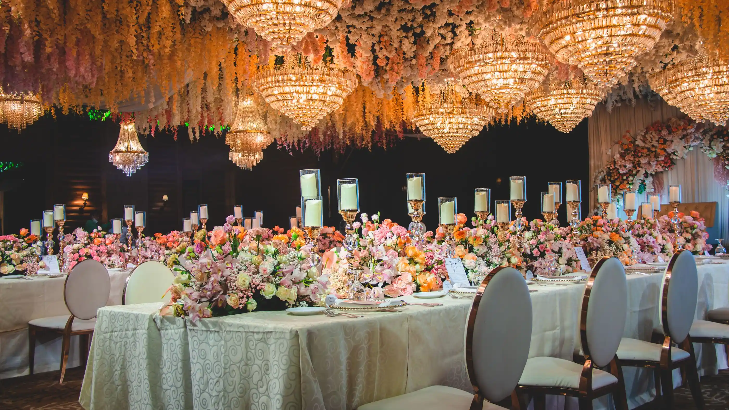 A hall dressed with chandeliers and flowers for a large dinner