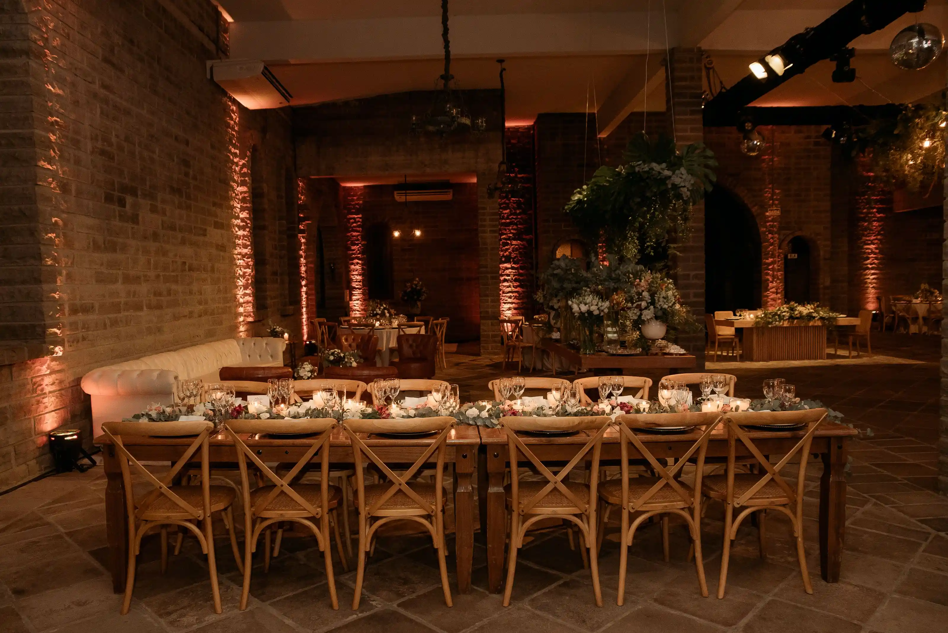 An indoor event space with wooden tables, chairs and foliage