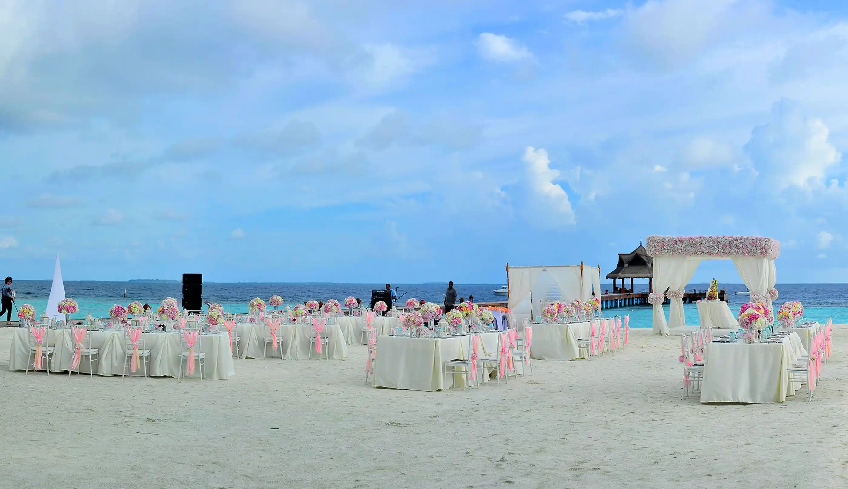Pastel florals framing a ceremony set on white sand