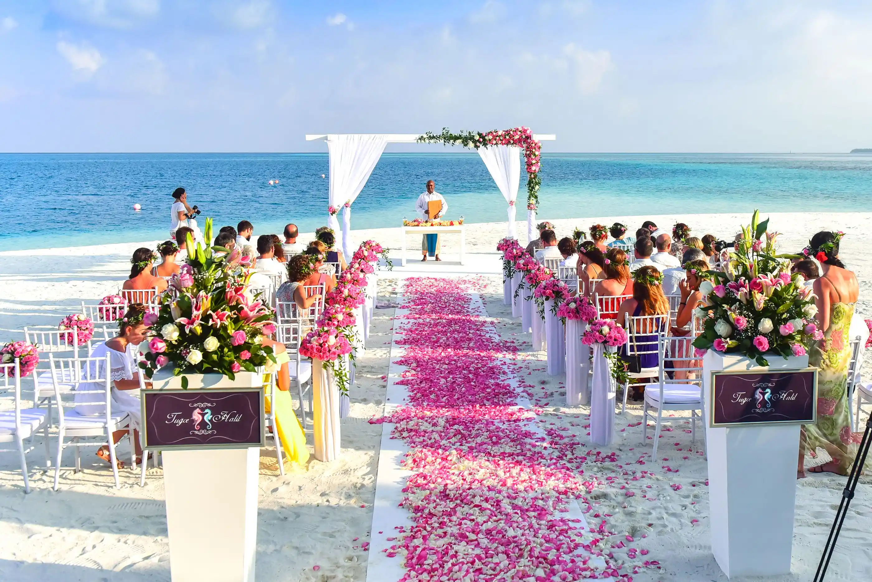 Guests seated for a beach ceremony with petals along the aisle