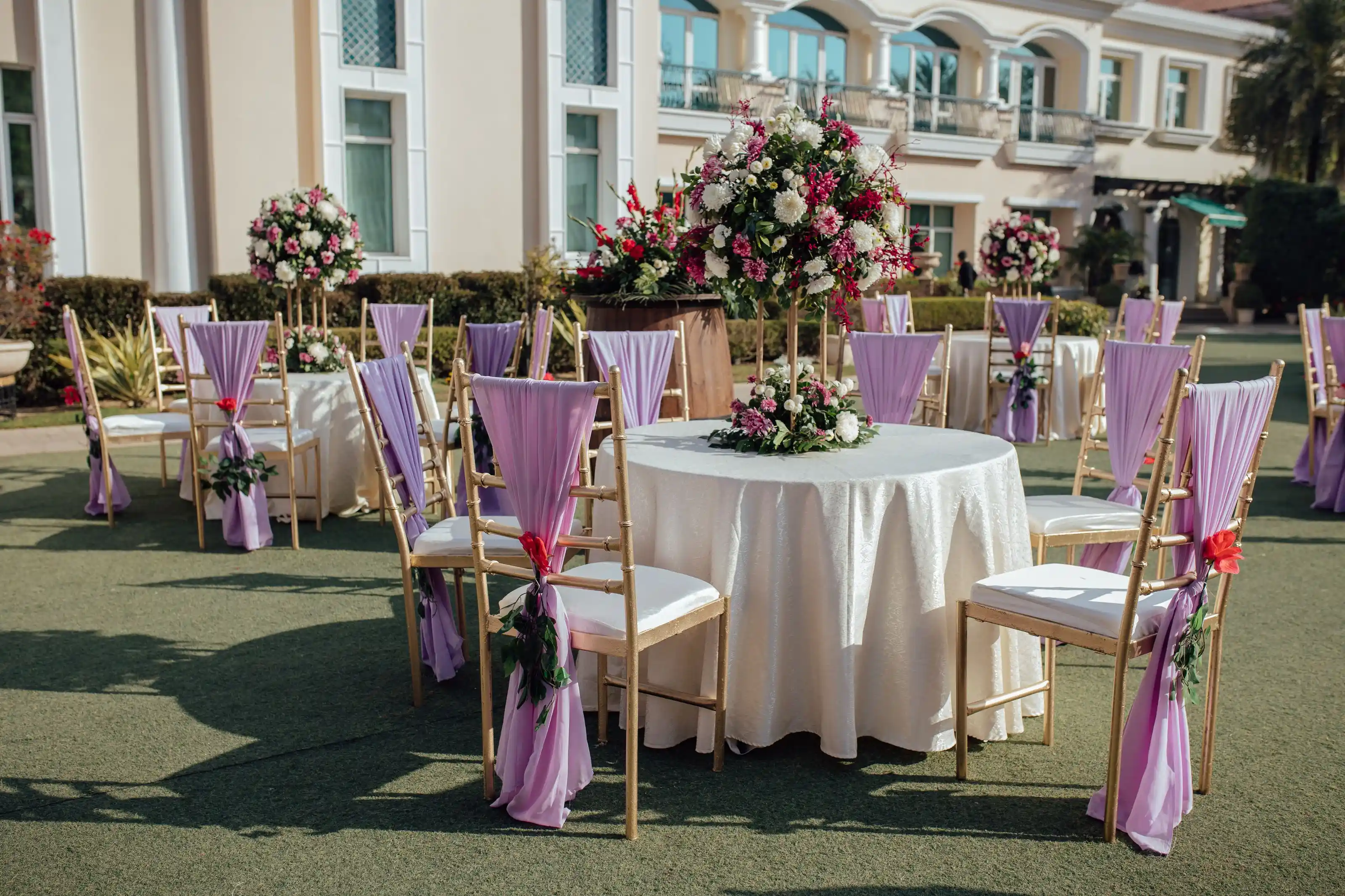 An outdoor reception with lavender arrangements beside a colonial facade