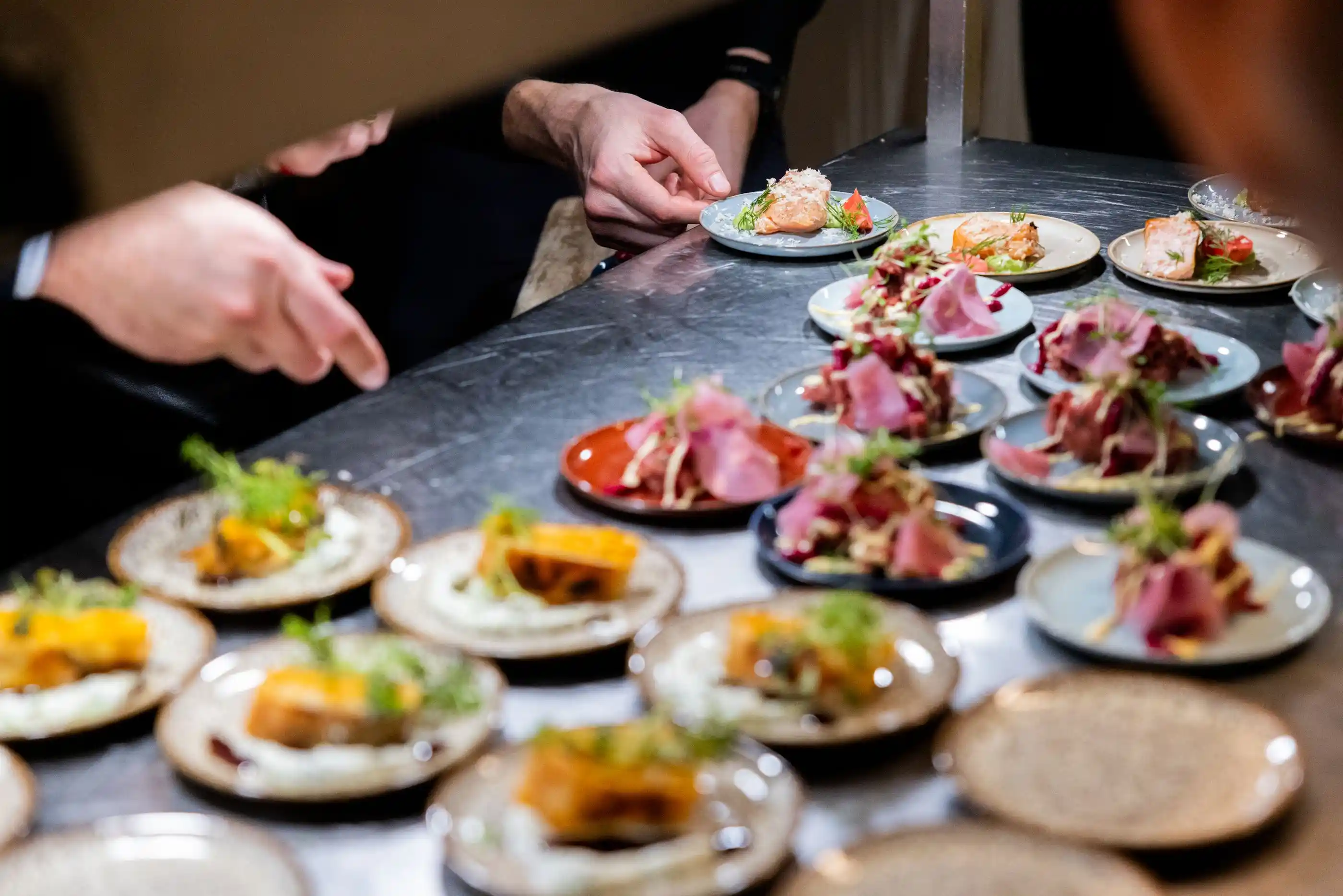 Chefs plating a tasting course at a live culinary station