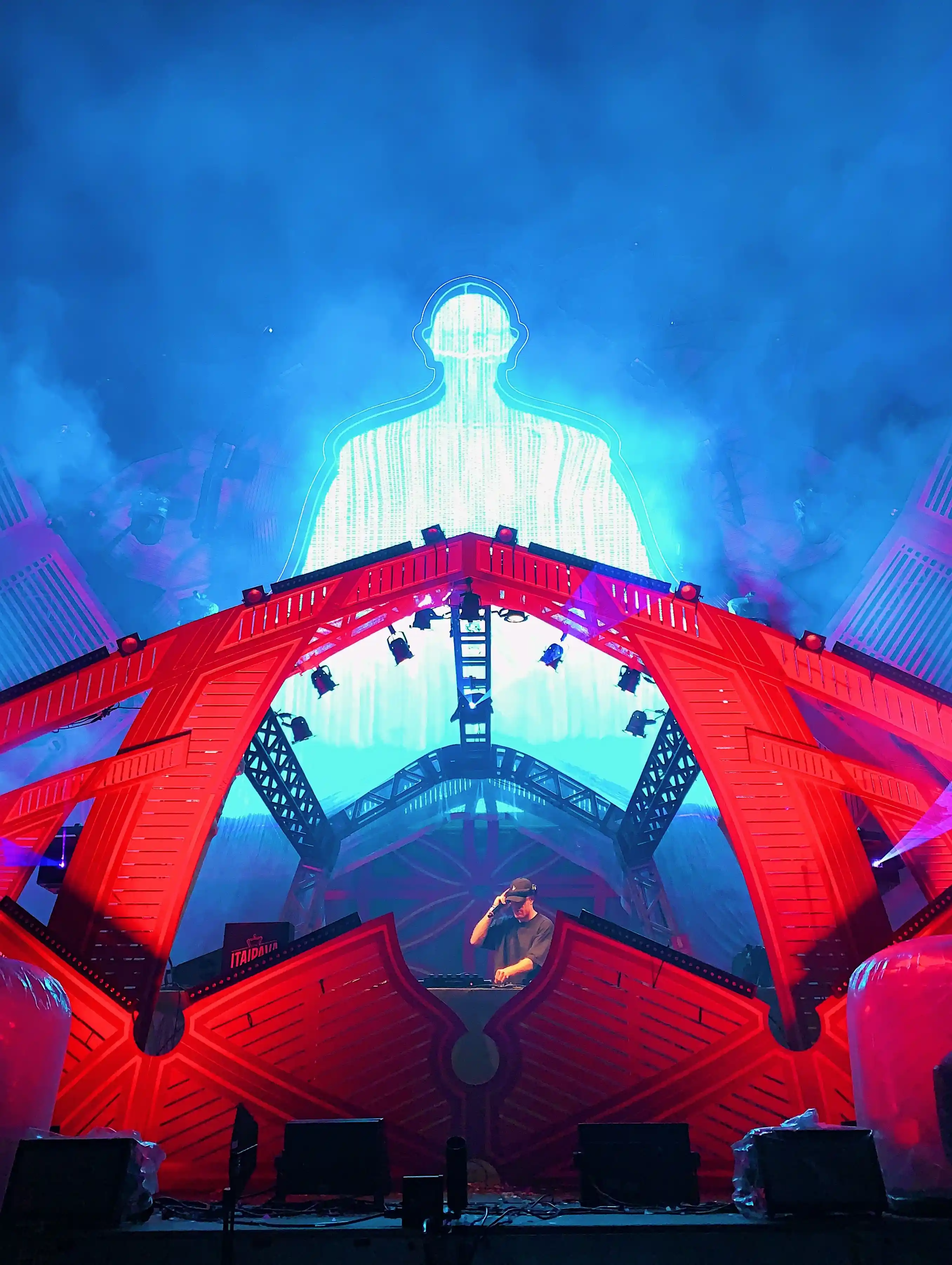 A stage built as a lit sculptural arch in red and blue
