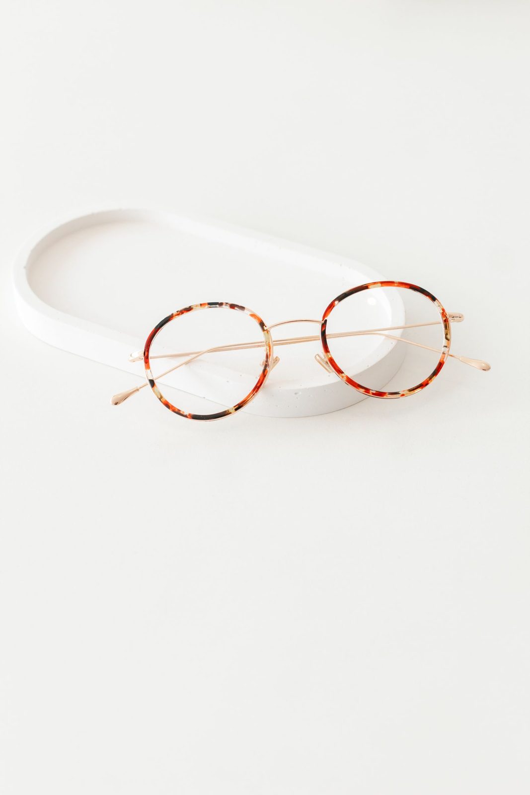 Round tortoiseshell spectacles resting on a white ceramic tray for Arden Optics