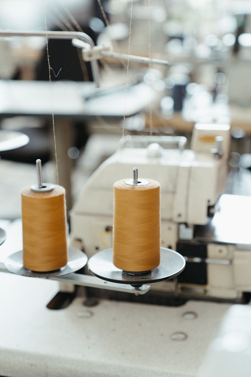 Close-up of an industrial sewing machine and thread spools in an atelier