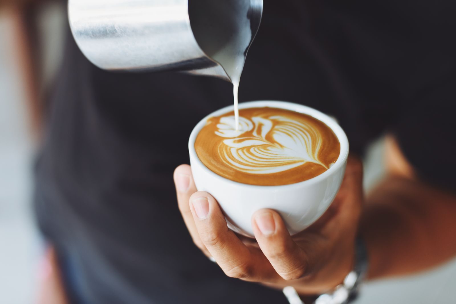 Barista pouring latte art into a white cup for Halden coffee