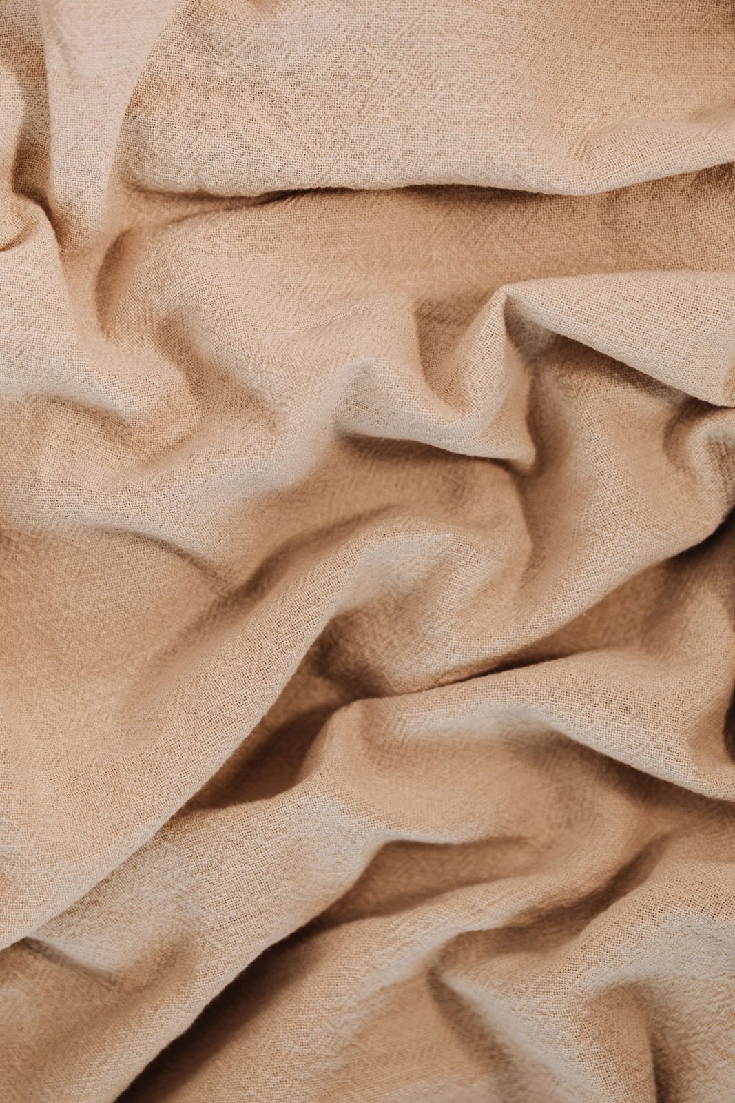 Crumpled terracotta-toned linen fabric filling the frame