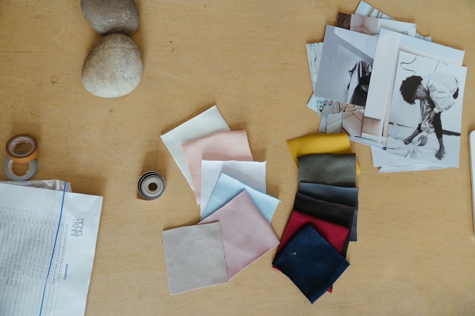 Fabric swatches, reference photographs and envelopes spread across a studio desk